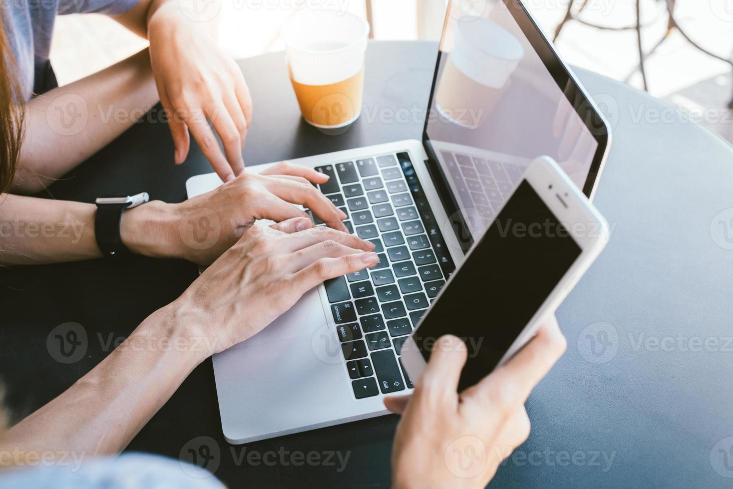 mujeres jóvenes asiáticas que trabajan en una computadora portátil usando y mirando un teléfono inteligente y tomando café mientras están sentadas en la cafetería. comunicación de mujeres de estilo de vida y trabajo en concepto de cafetería. foto