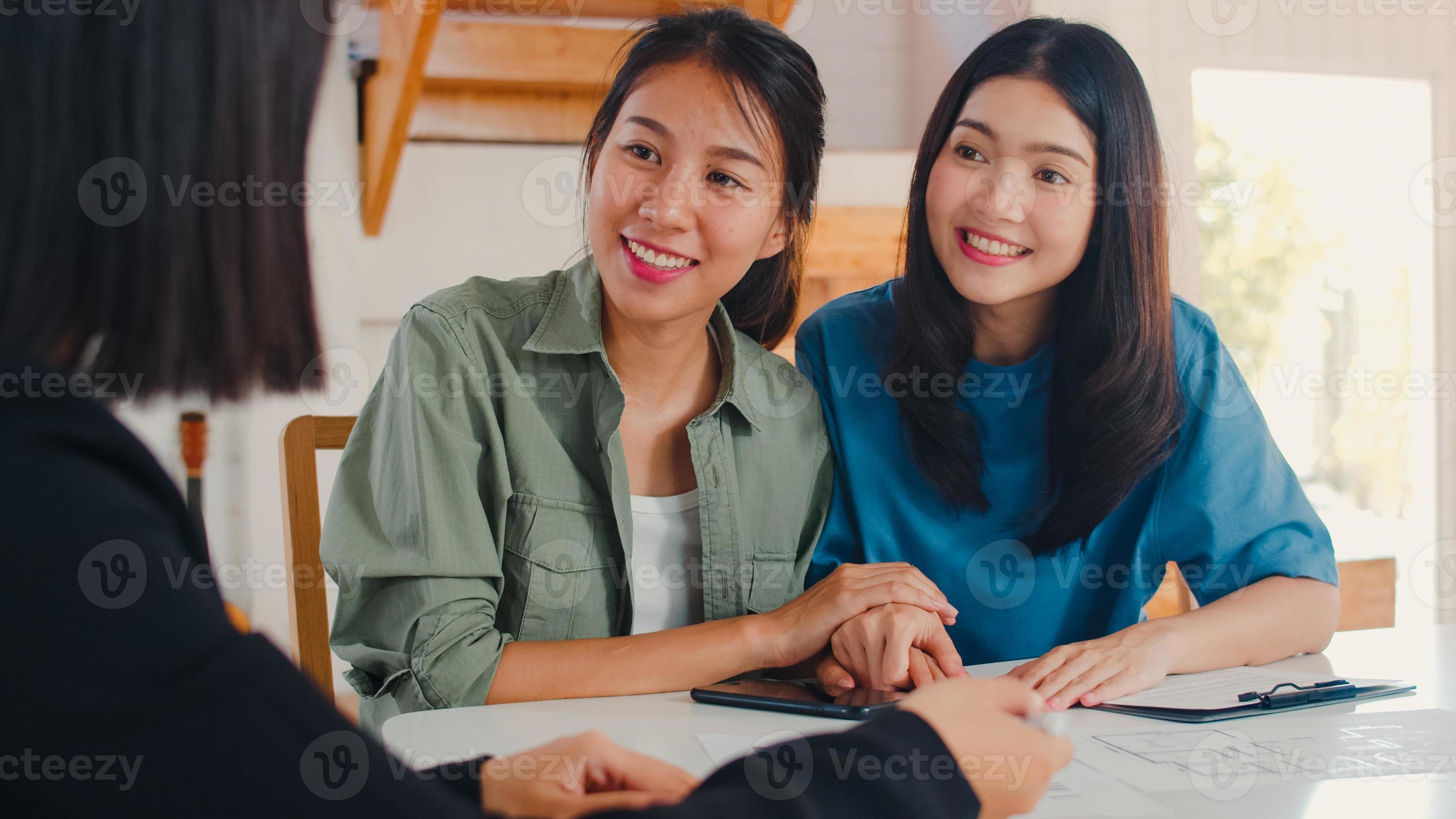 una pareja de mujeres lesbianas lgbtq asiáticas firma un contrato en casa, una pareja joven consulta con un asesor financiero de bienes raíces, compra una casa nueva y se da la mano con un corredor en el concepto de sala de estar. foto