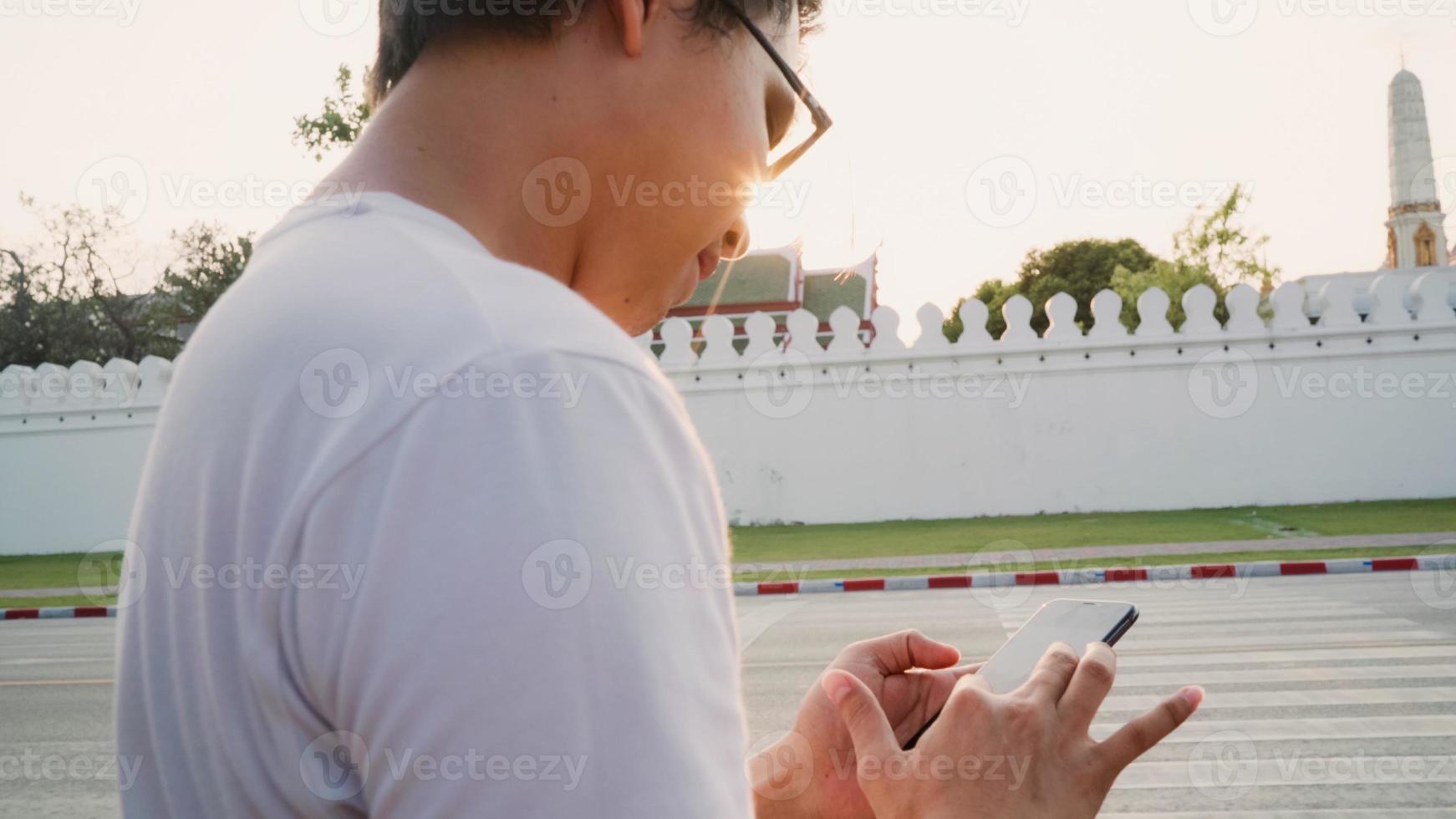 dirección del hombre asiático del viajero en el mapa de ubicación en bangkok, tailandia, hombre mochilero usando un teléfono móvil mirando en el mapa mientras pasa un viaje de vacaciones al atardecer. los hombres de estilo de vida viajan en el concepto de ciudad de asia. foto