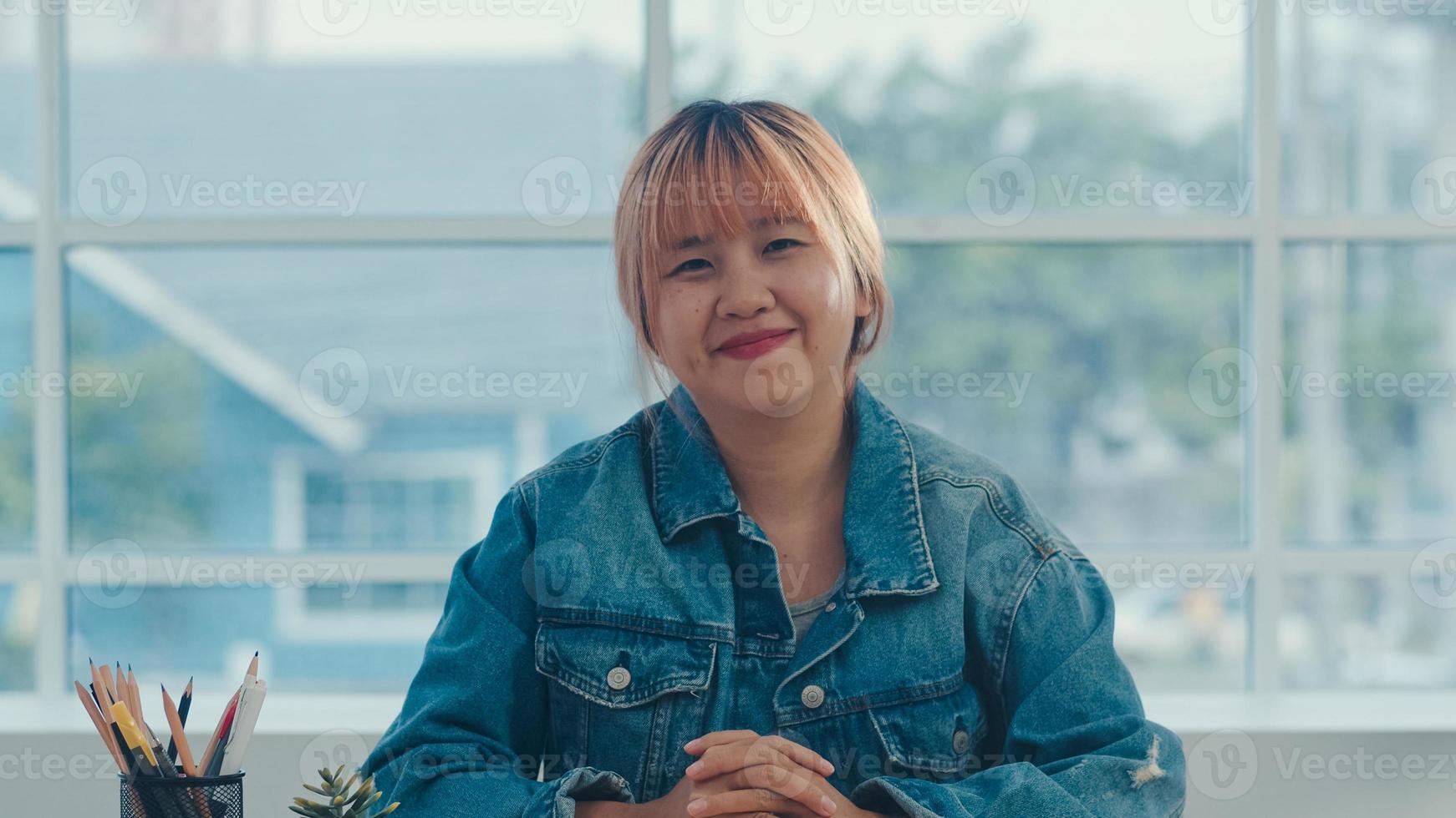 Young Asian creative woman smiling in office. Business female happy relax after work, looking to camera, business situation in modern workplace concept. photo