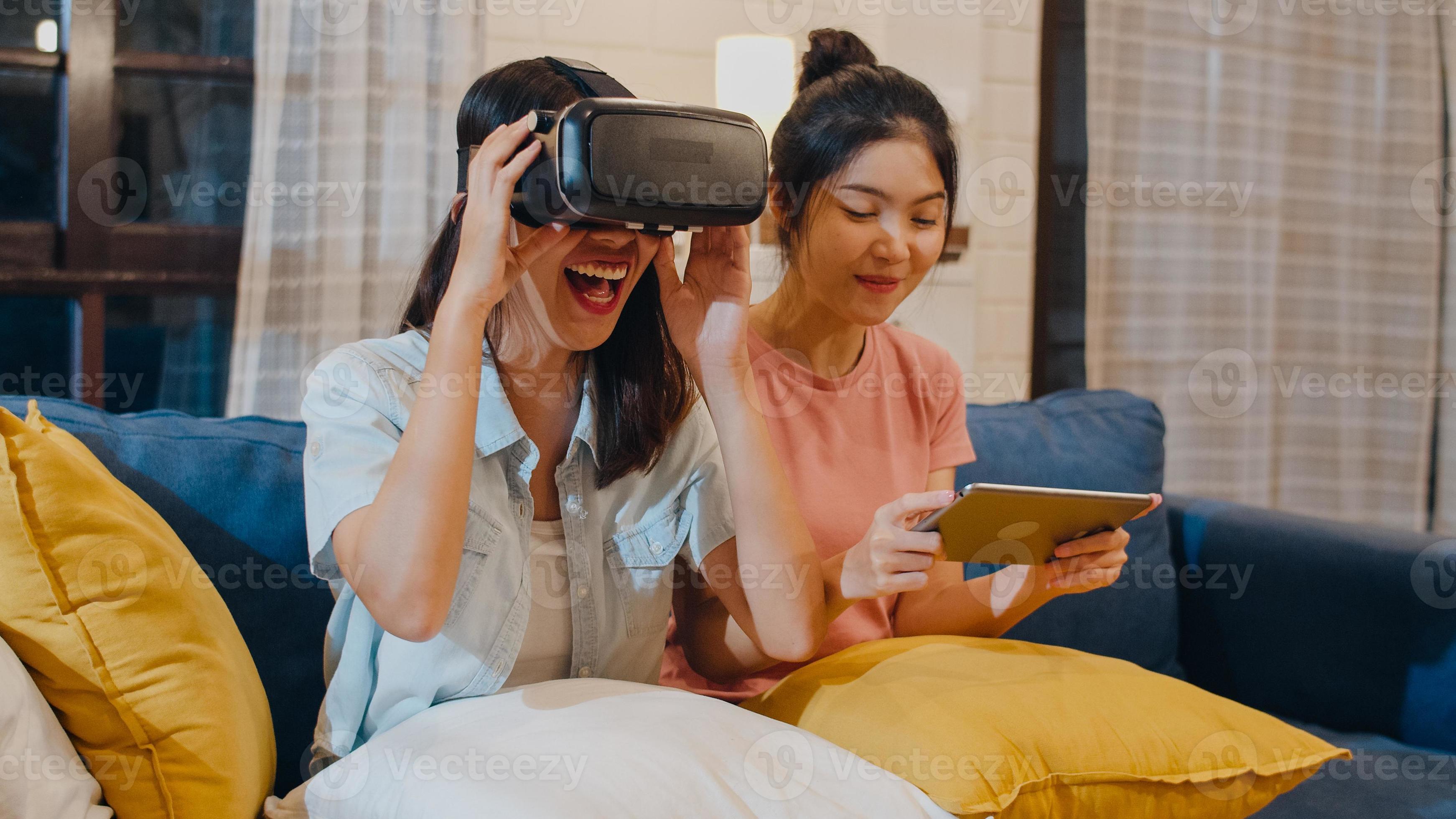 George Bernard Konvention Dum Lesbian lgbt women couple using tablet at home, Asian female feeling happy  using laptop and VR playing games together while lying sofa in living room  in night. Lover celebrate holiday concept. 5486894