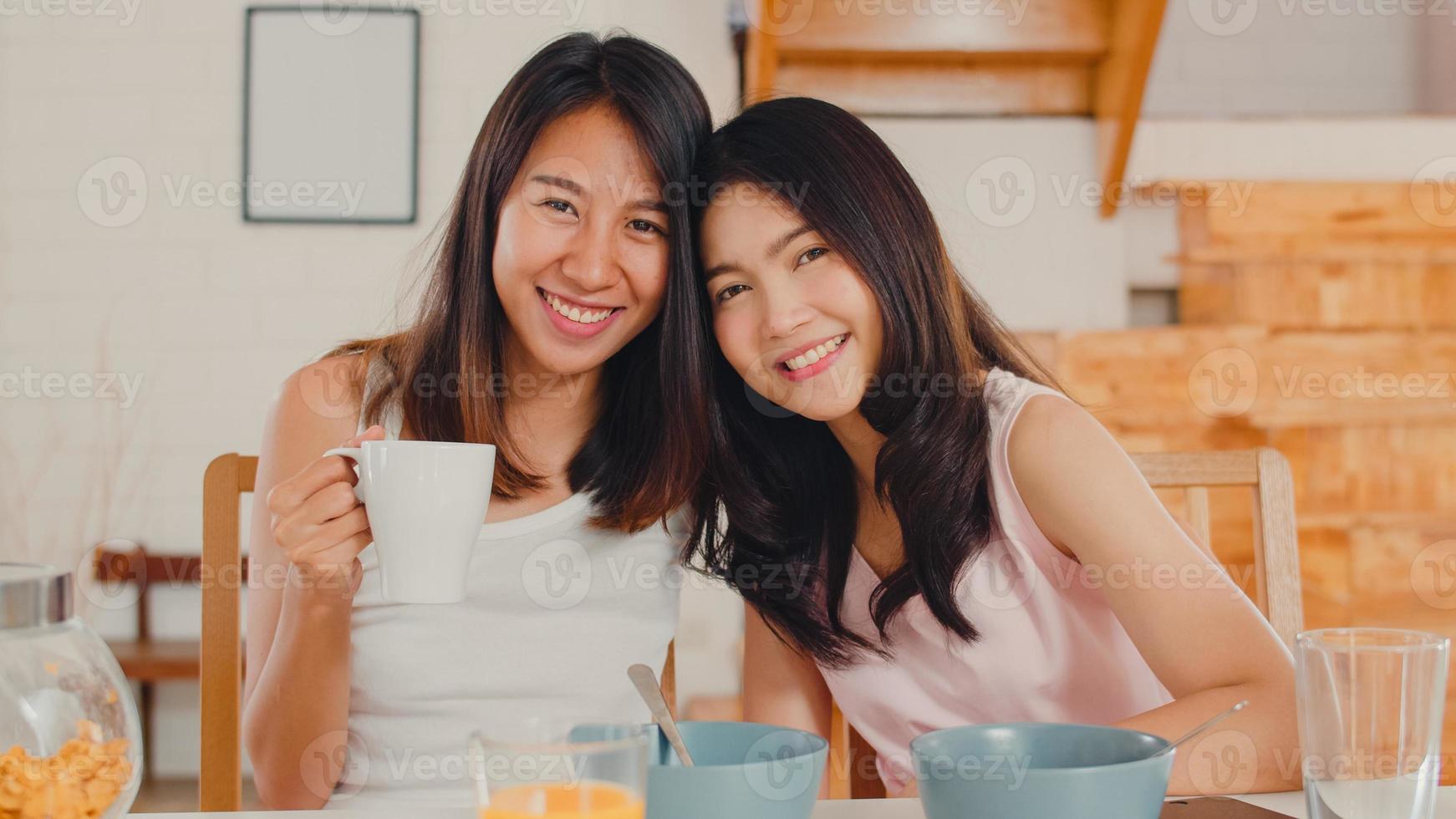 Asian Lesbian lgbtq women couple have breakfast at home, Young Asia lover girls feeling happy toothy smile looking to camera while eat cereal and milk on table in kitchen in the morning concept. photo