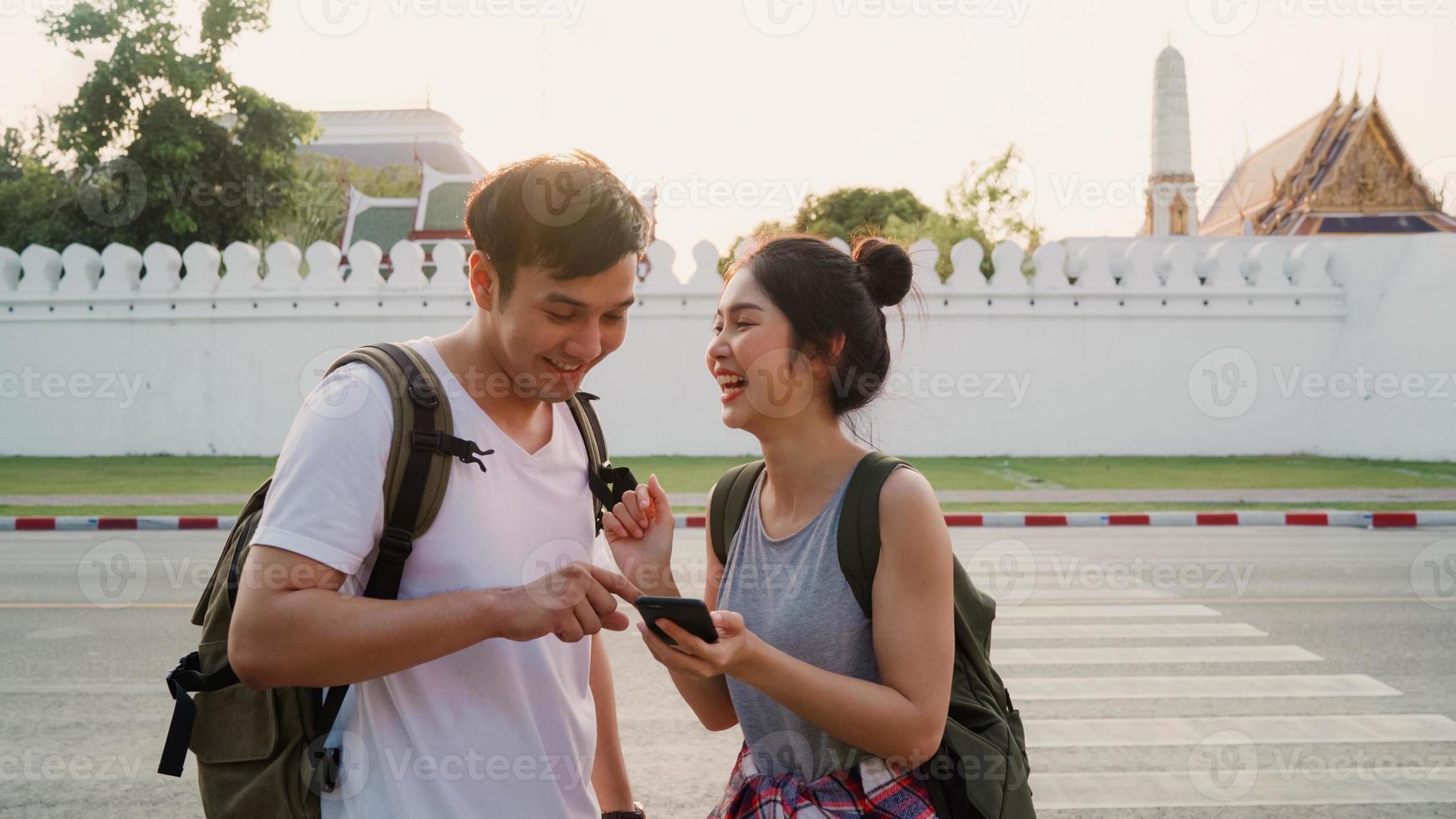 dirección de la pareja asiática del viajero en el mapa de ubicación en bangkok, tailandia, pareja dulce que usa el teléfono móvil mirando en el mapa mientras pasa un viaje de vacaciones al atardecer. pareja de estilo de vida viaja en concepto de ciudad. foto