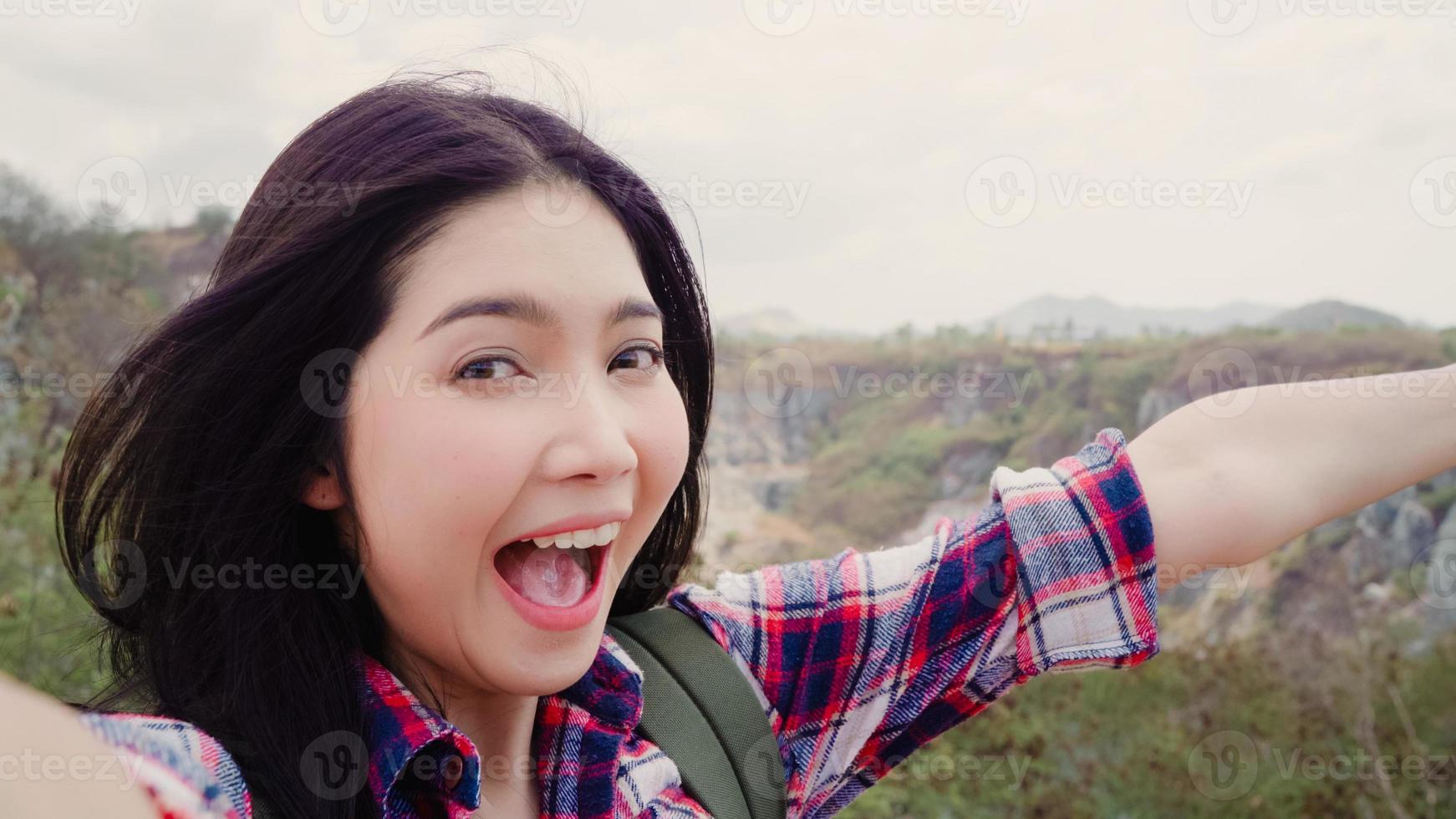 Blogger Asian backpacker woman record vlog video on top of mountain, young female happy using mobile phone make vlog video enjoy holidays on hiking adventure. Lifestyle women travel and relax concept. photo