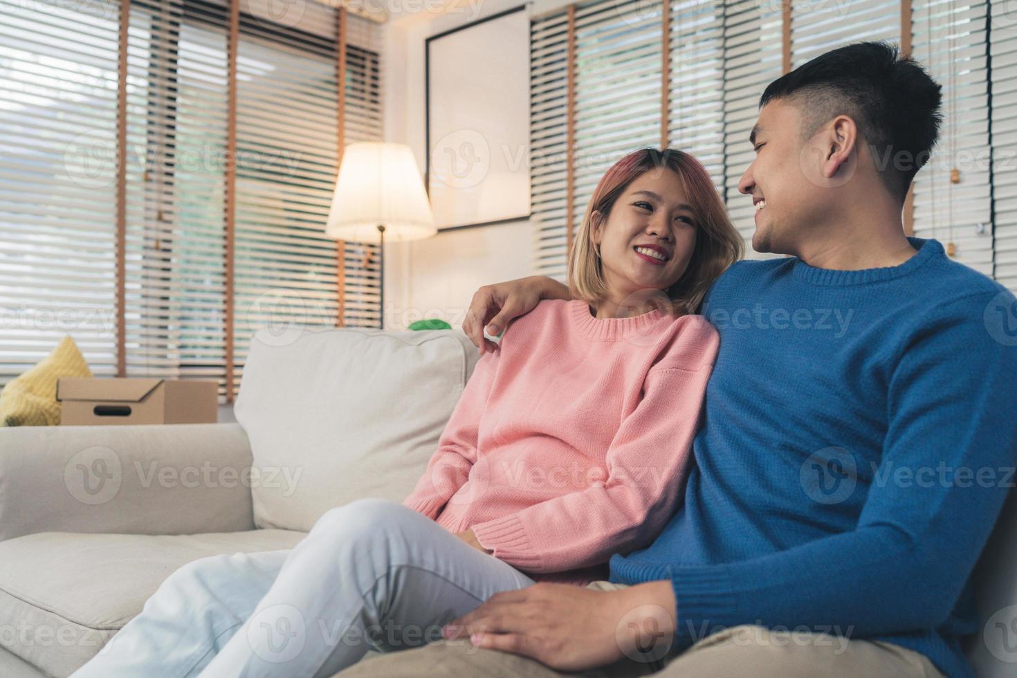 dulce y feliz pareja asiática joven que mueve ropa y muchos objetos de la vieja casa a su nueva casa y se relaja en el sofá en la sala de estar de su casa. la pareja de estilo de vida se muda a un nuevo hogar. foto