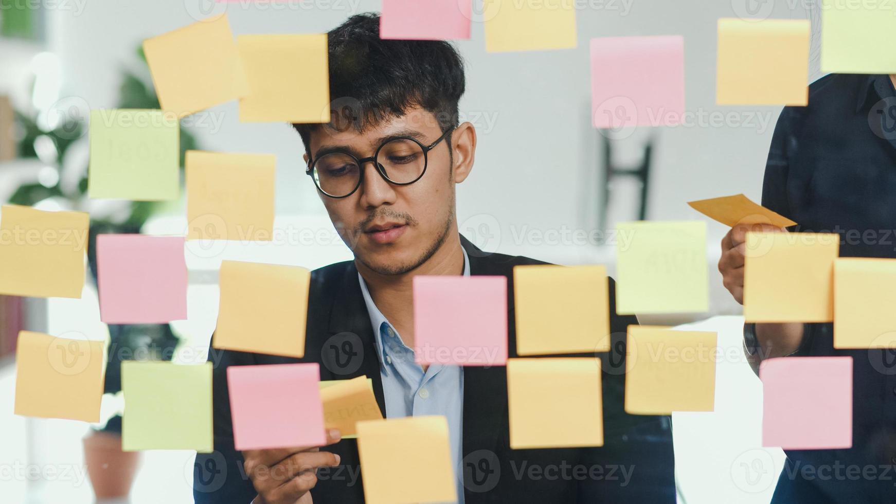 Group of Asian creative men workshop and brainstorm in front of mirror board. Young professional business team working create strategy, business situation, startup in Loft office concept. photo