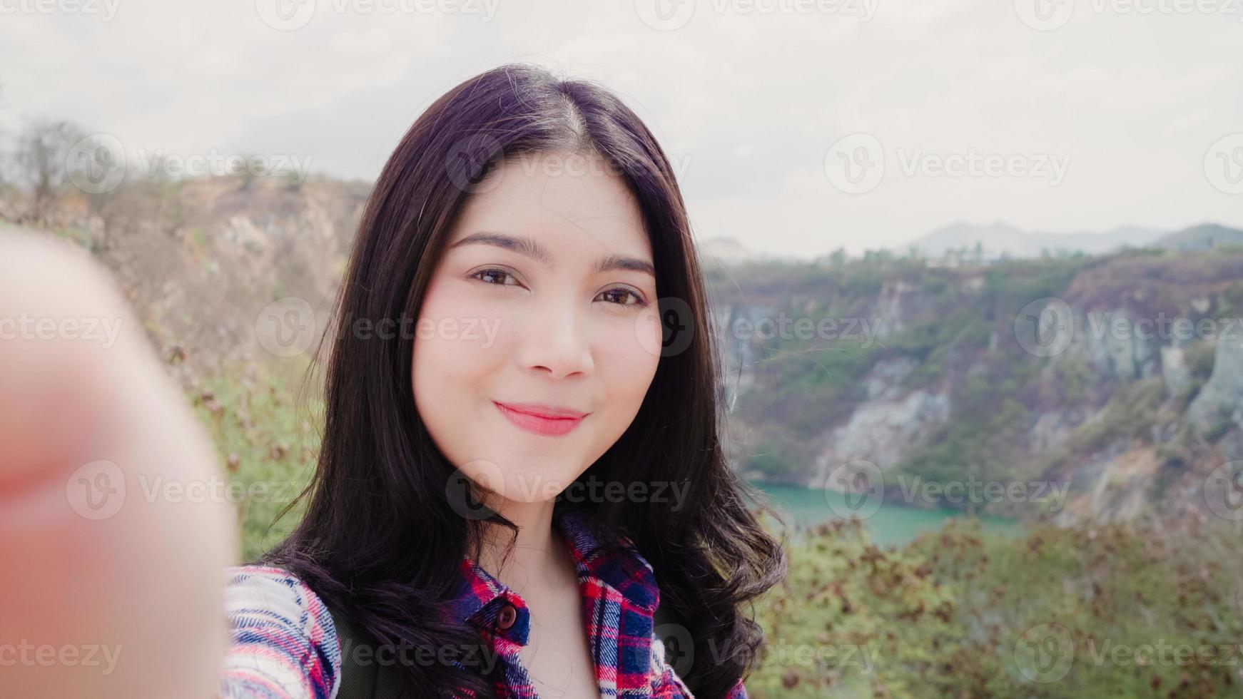 Blogger Asian backpacker woman record vlog video on top of mountain, young female happy using mobile phone make vlog video enjoy holidays on hiking adventure. Lifestyle women travel and relax concept. photo