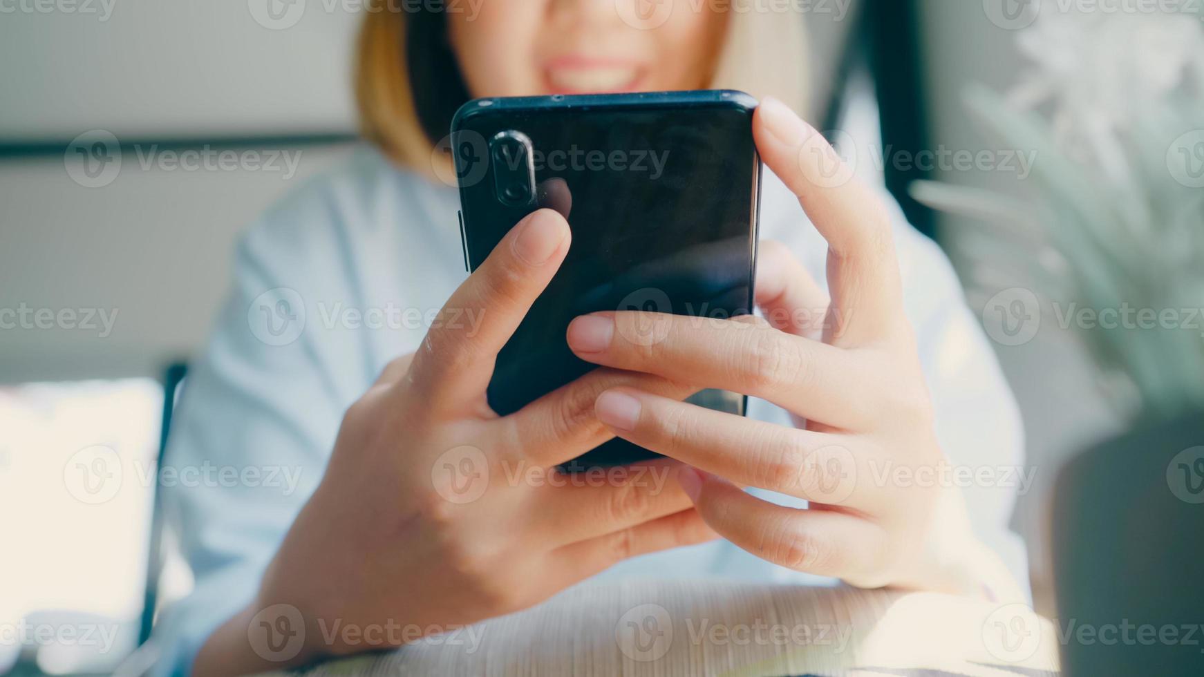 Business freelance Asian woman using smartphone for talking, reading and texting while sitting on table in cafe. Lifestyle smart beautiful women working at coffee shop concept. photo