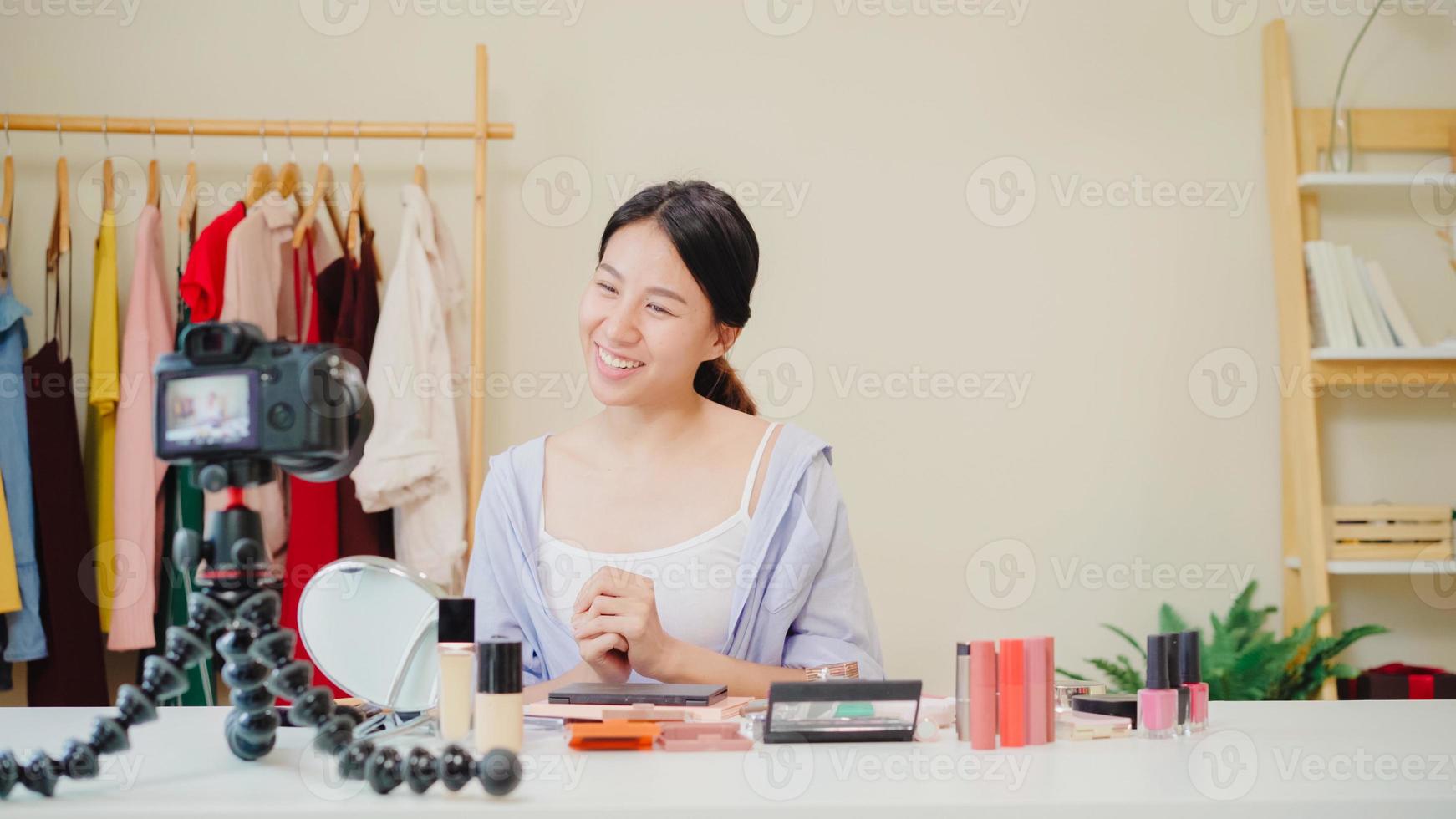 Beauty blogger present beauty cosmetics sitting in front camera for recording video. Beautiful asian woman use cosmetics review make up tutorial broadcast live video to social network by internet. photo