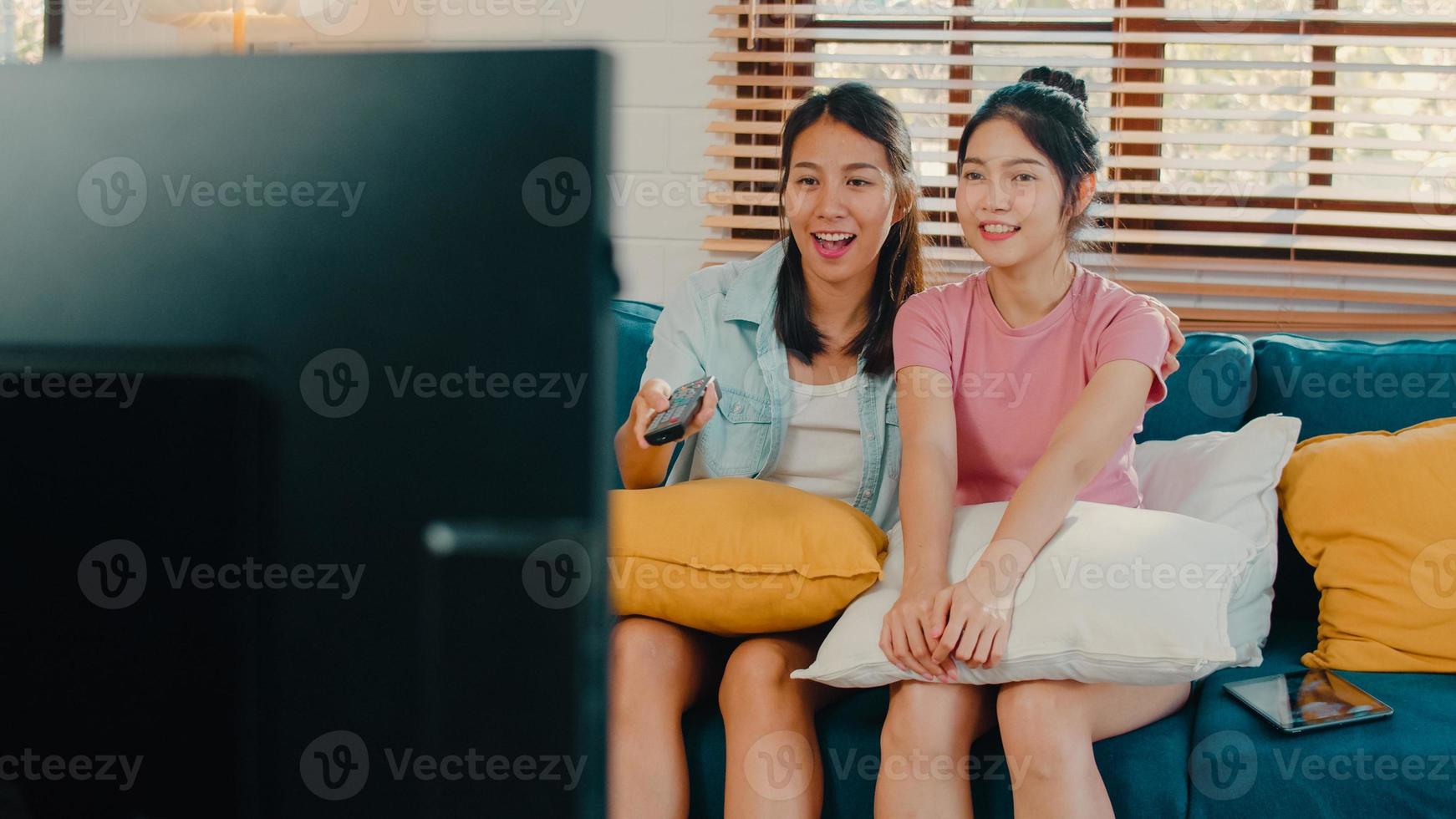 jóvenes asia lesbianas lgbtq mujeres pareja viendo televisión en casa, amante asiática mujer sintiéndose feliz diversión reír mirando series de televisión juntos mientras están acostados en el sofá en la sala de estar en el concepto de hogar. foto
