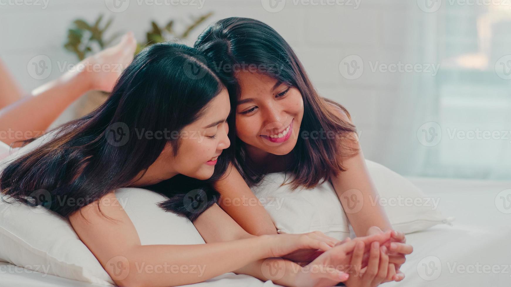 Asian Lesbian lgbtq women couple talking on bed at home. Young Asia lover female happy relax rest together after wake up while lying on bed in bedroom at home in the morning concept. photo