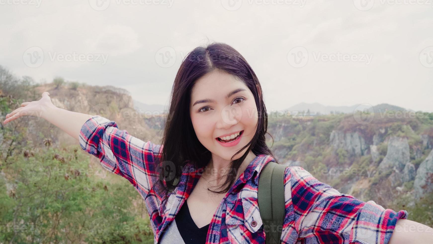 Blogger Asian backpacker woman record vlog video on top of mountain, young female happy using mobile phone make vlog video enjoy holidays on hiking adventure. Lifestyle women travel and relax concept. photo