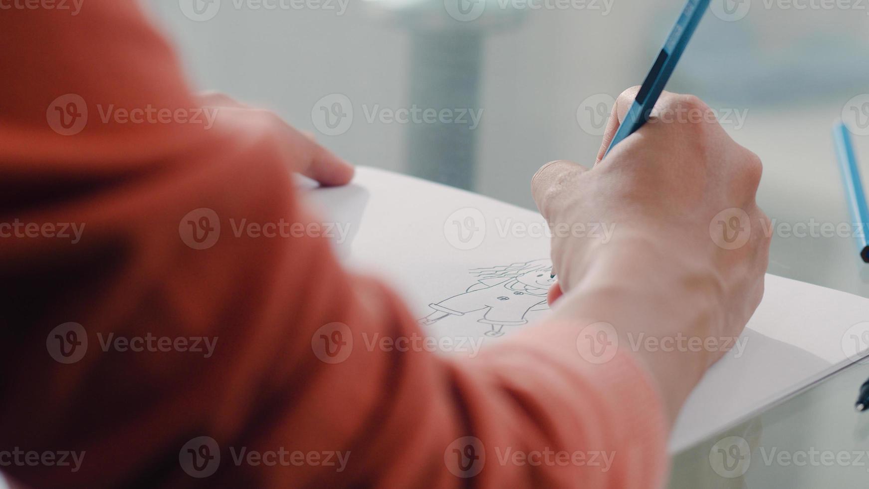 Young Asian Pregnant woman drawing baby in belly and family in notebook. Mom feeling happy smiling positive and peaceful while take care child on table in living room at home concept. photo