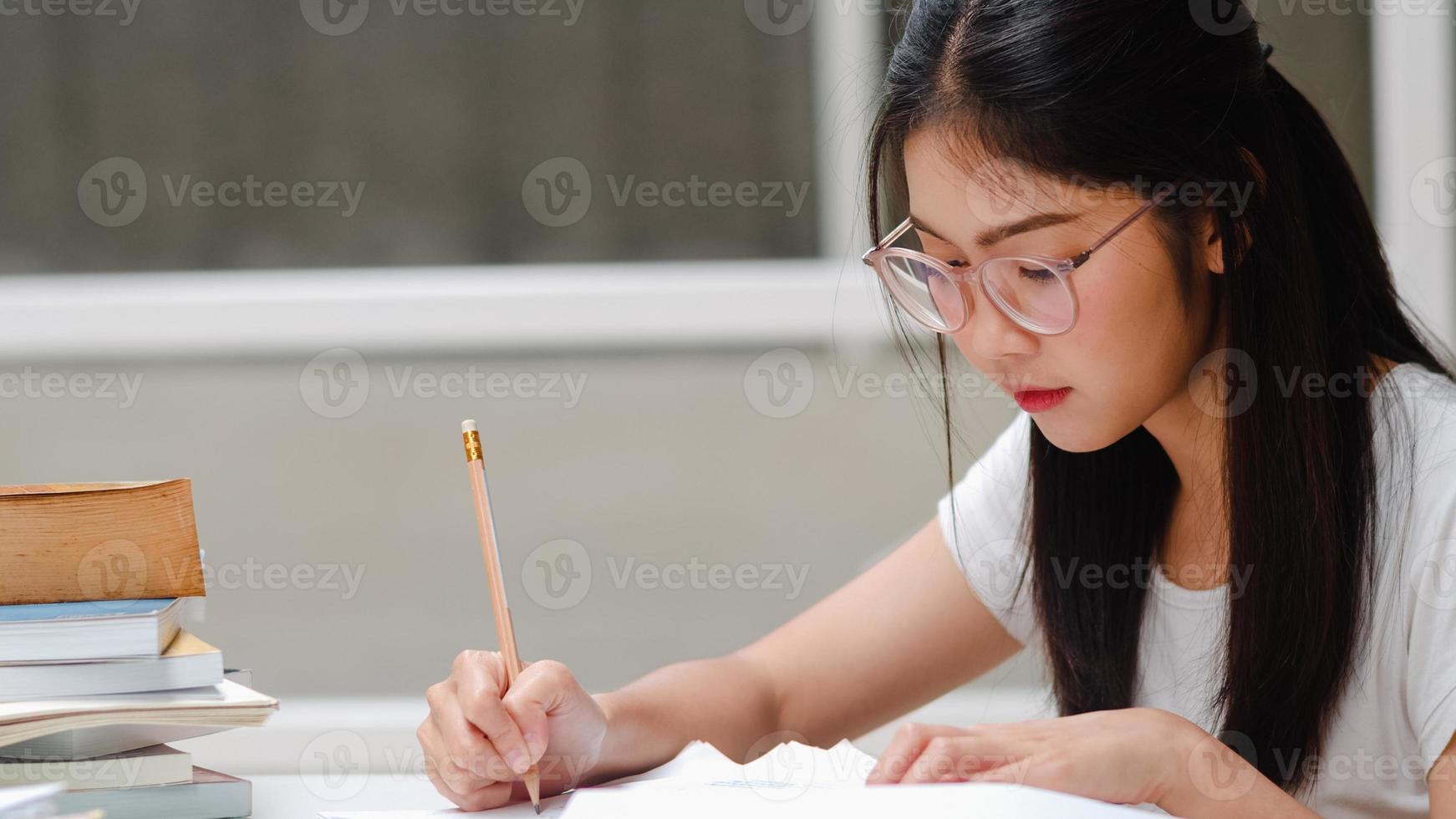 Asian student women reading books in library at university. Young undergraduate girl do homework, read textbook, study hard for knowledge and education on lecture desk at college campus. photo