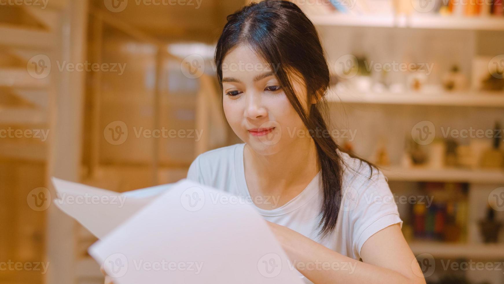 Asian student women reading books in library at university. Young undergraduate girl do homework, read textbook, study hard for knowledge on lecture desk at college campus overtime night. photo