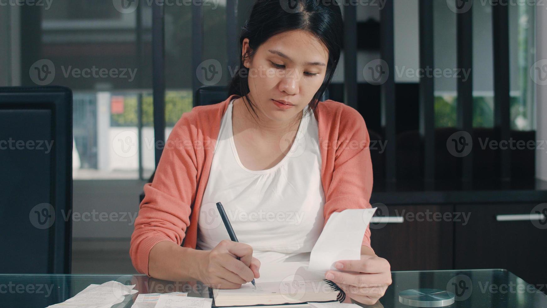 Registros de ingresos y gastos en el hogar de una joven asiática embarazada. mamá niña feliz usando el presupuesto de registro de la computadora portátil, impuestos, documentos financieros, comercio electrónico trabajando en el concepto de sala de estar en casa. foto