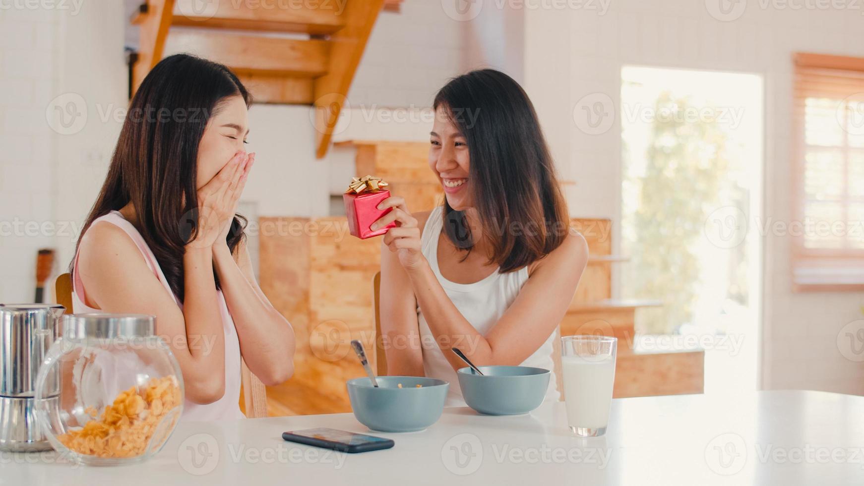 Asian Lesbian lgbtq women couple giving present home, Young Asia lover girls happy surprise on her birthday or Valentines day while have breakfast in kitchen in the morning concept. photo