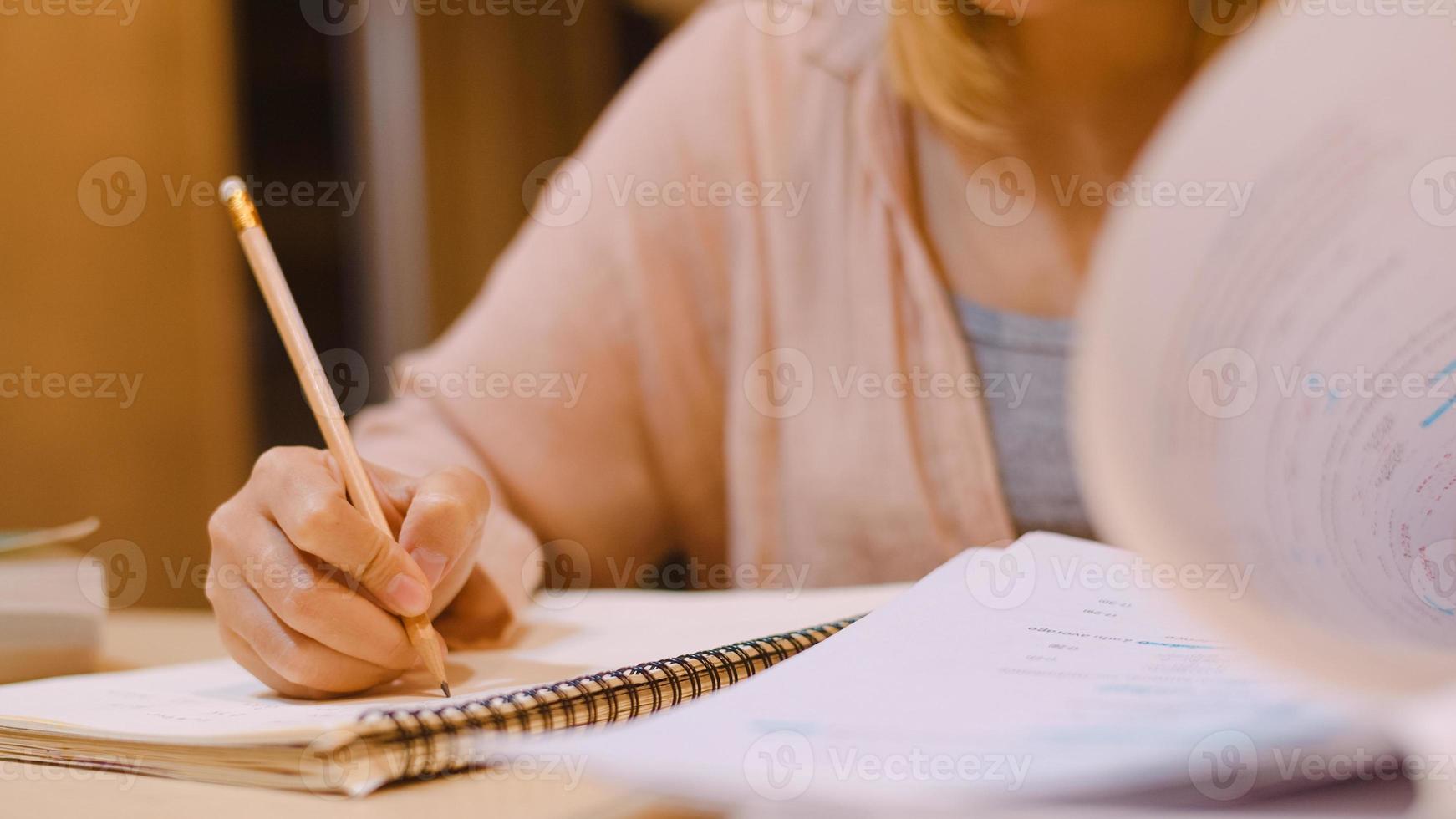 Asian student women reading books in library at university. Young undergraduate girl do homework, read textbook, study hard for knowledge on lecture desk at college campus overtime night. photo