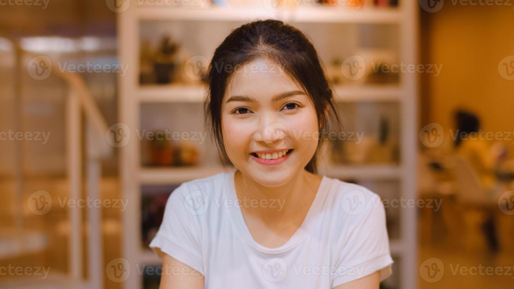 Portrait Asian Chinese woman feeling happy smiling in library at university. Young undergraduate teen girl relax toothy smile looking to camera at college campus overtime at night concept. photo