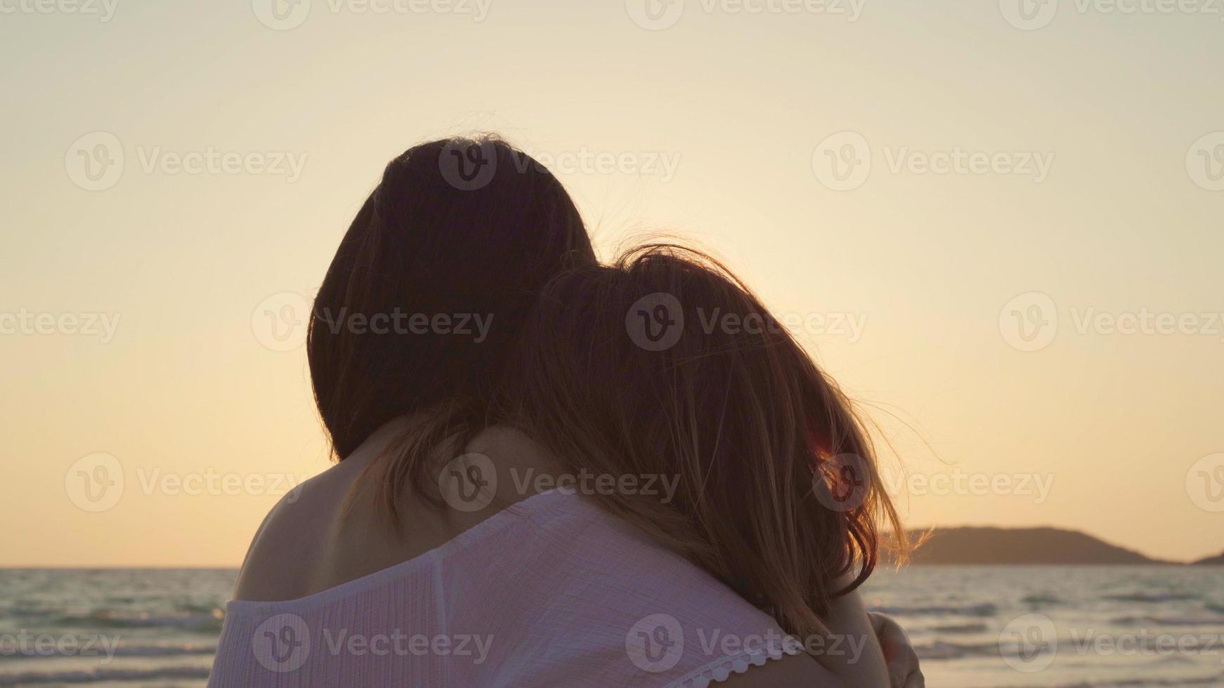 Young Asian lesbian couple kissing near beach. Beautiful women lgbt couple happy relax enjoy love and romantic moment when sunset in evening. Lifestyle lesbian couple travel on beach concept. photo