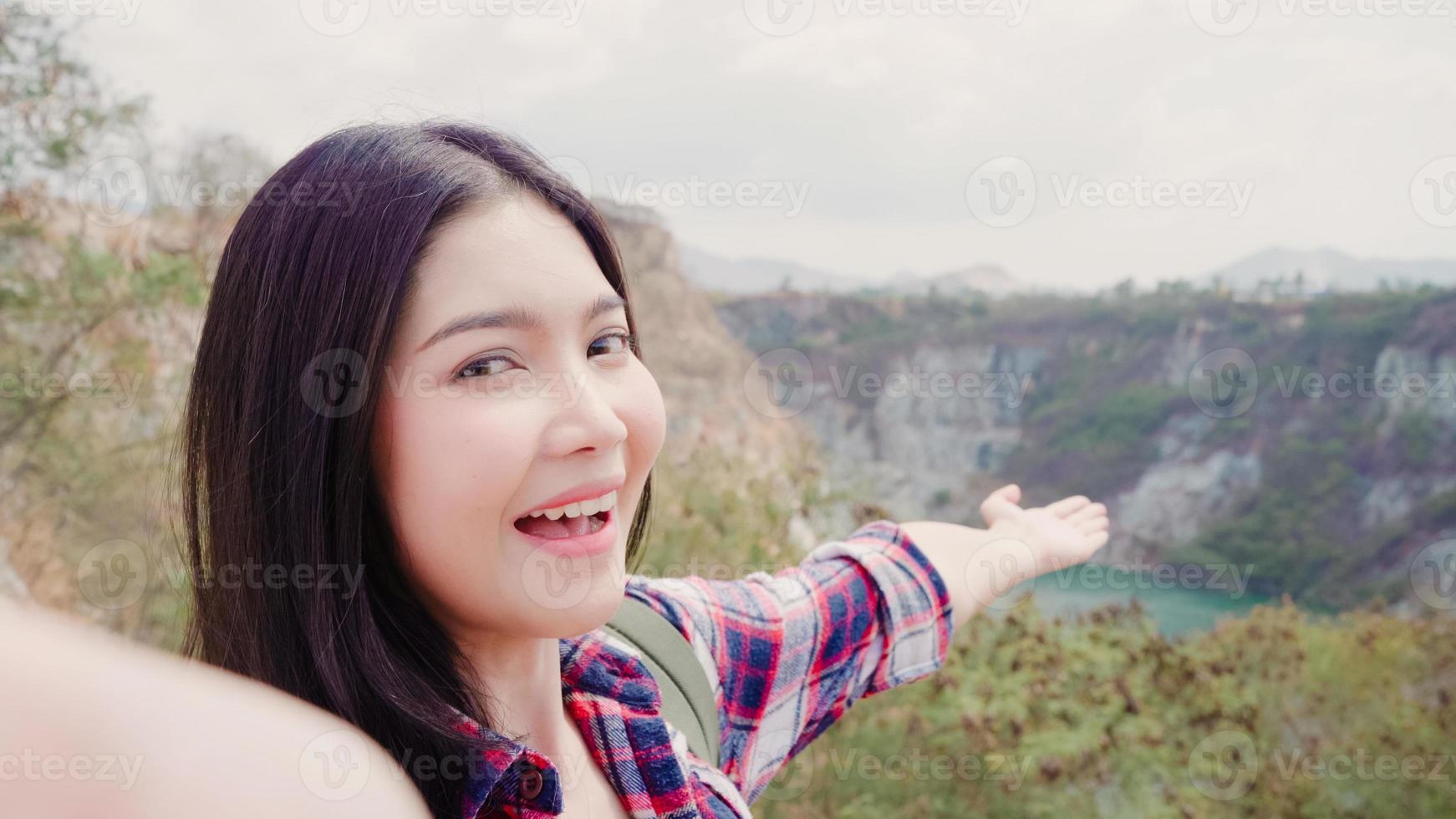 Blogger Asian backpacker woman record vlog video on top of mountain, young female happy using mobile phone make vlog video enjoy holidays on hiking adventure. Lifestyle women travel and relax concept. photo