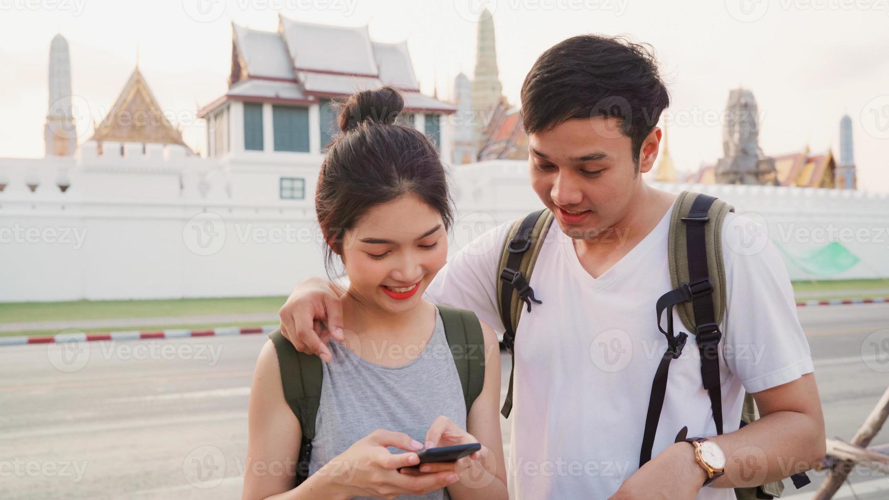 Traveler Asian couple direction on location map in Bangkok, Thailand, sweet couple using mobile phone looking on map while spending holiday trip in sunset. Lifestyle couple travel in city concept. photo