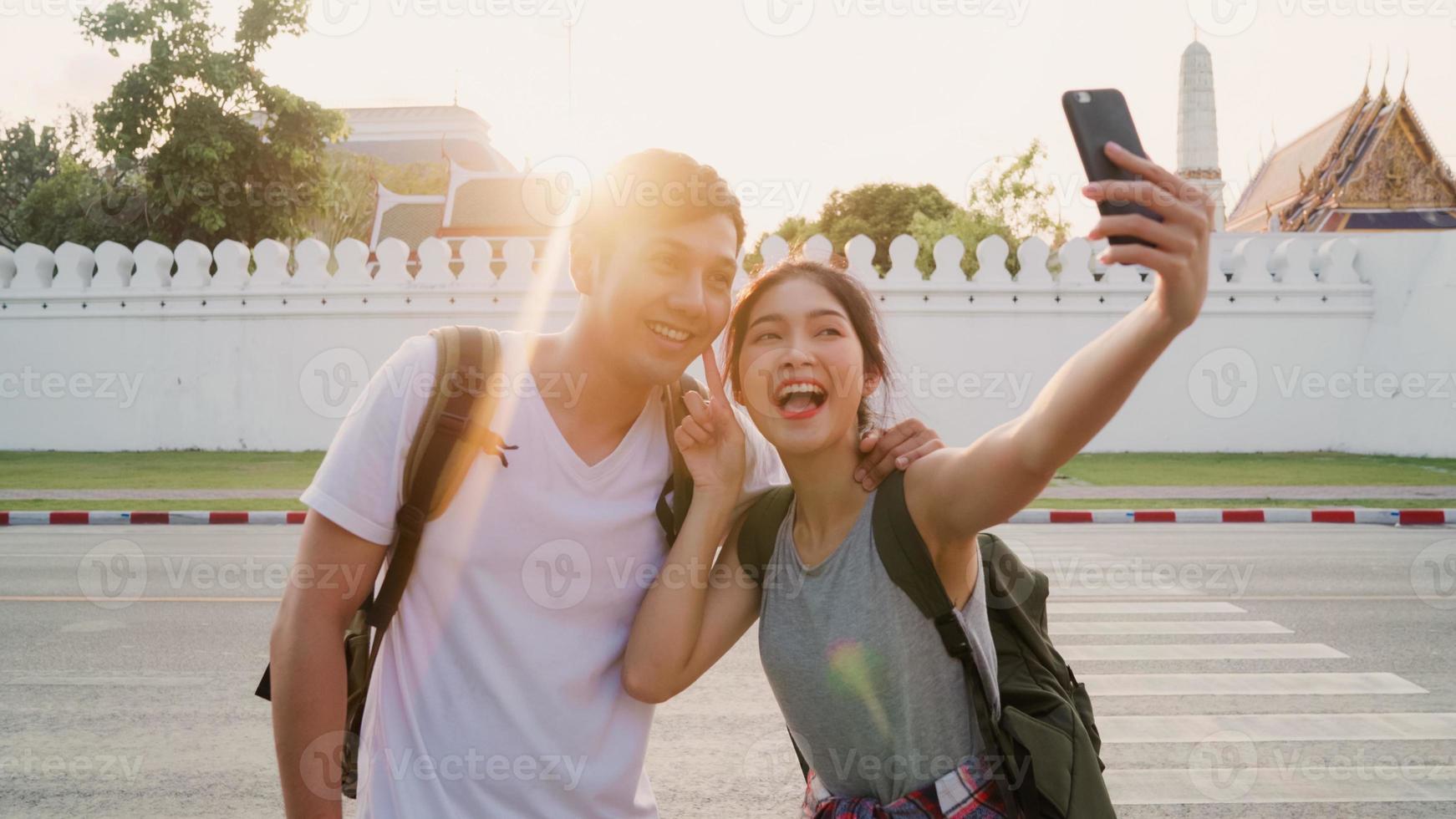 una pareja de blogueras asiáticas viaja en bangkok, tailandia, una pareja dulce usando selfie de teléfono móvil y vista de fotos mientras pasa un tiempo dulce en un viaje de vacaciones al atardecer. pareja viaja en concepto de ciudad.