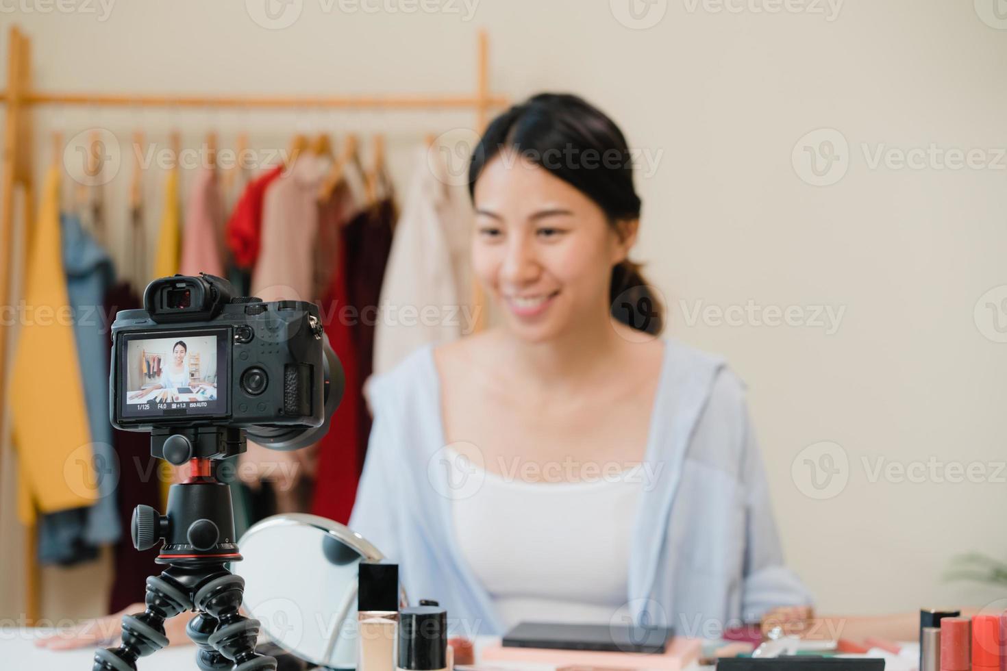 Beauty blogger present beauty cosmetics sitting in front camera for recording video. Beautiful asian woman use cosmetics review make up tutorial broadcast live video to social network by internet. photo