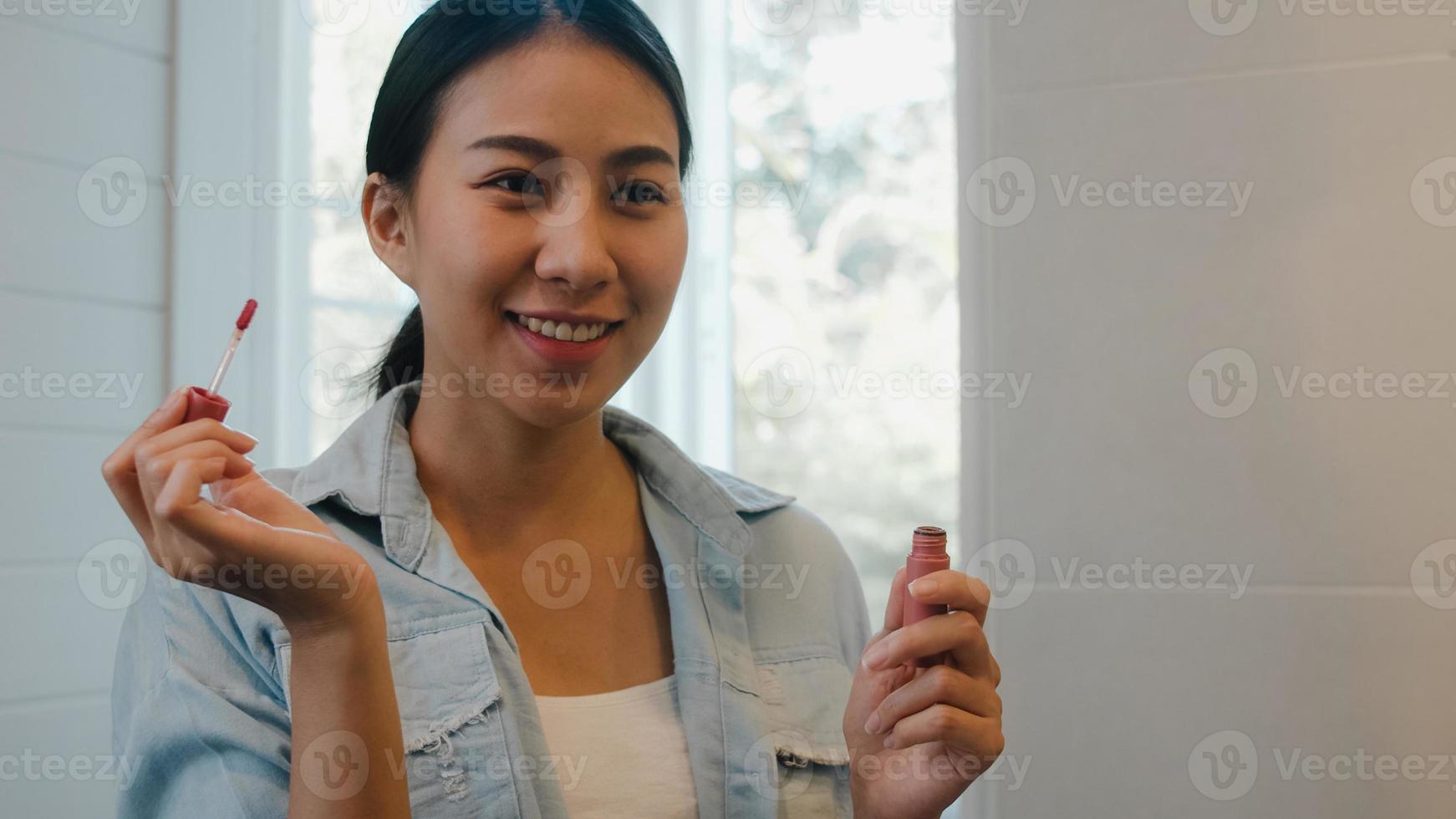 Beautiful Asian woman using lipstick make up in front mirror, Happy Chinese female using beauty cosmetics to improve herself ready to working in bathroom at home. Lifestyle women relax at home concept photo