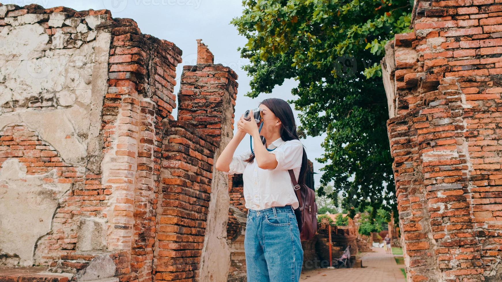 Traveler Asian woman using camera for take a picture while spending holiday trip at Ayutthaya, Thailand, Japanese female tourist enjoy her journey at amazing landmark in traditional city. photo