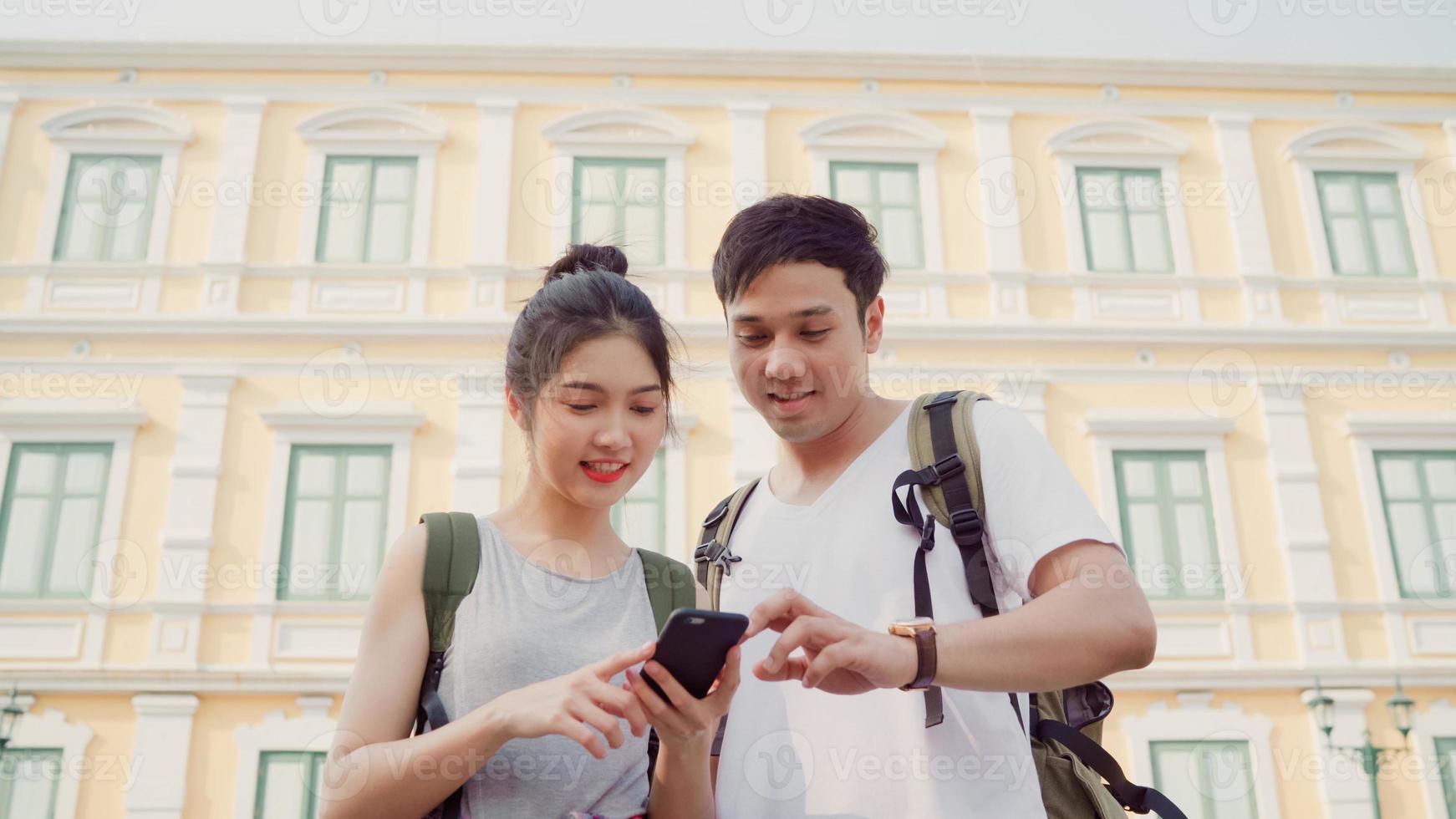Traveler Asian couple direction on location map in Bangkok, Thailand, couple using mobile phone looking on map find landmark while spending holiday trip. Lifestyle couple travel in city concept. photo