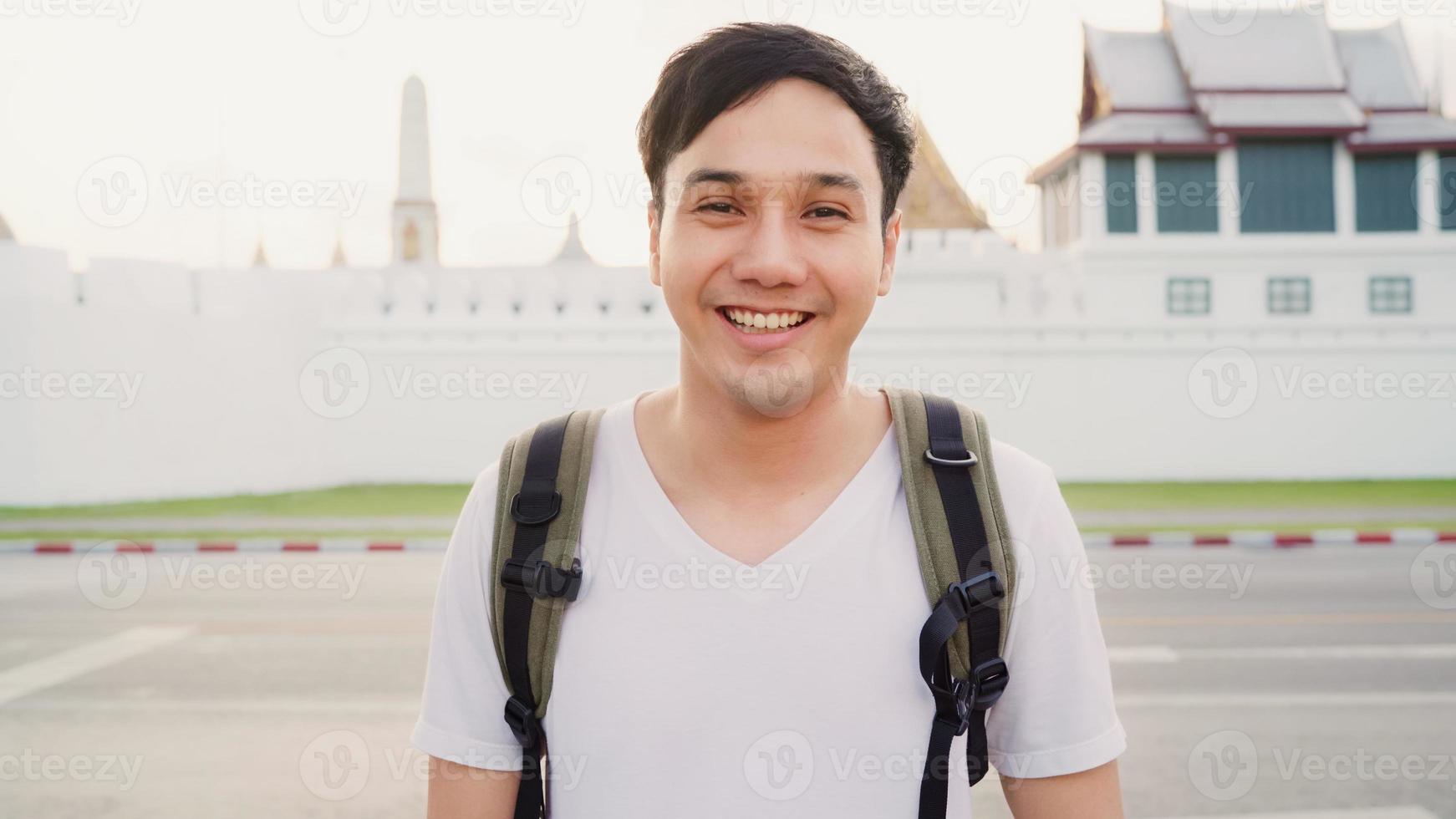 viajero hombre asiático que se siente feliz sonriendo a la cámara viaje de vacaciones en bangkok, tailandia, mochilero asia macho disfruta de su viaje en un hito increíble en la ciudad tradicional. retrato mirando a la cámara. foto