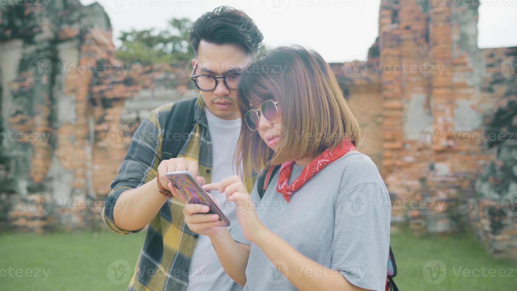 Traveler Asian couple using smartphone for direction and looking on location map while spending holiday trip at Ayutthaya, Thailand, backpacker sweet couple enjoy journey in traditional city. photo