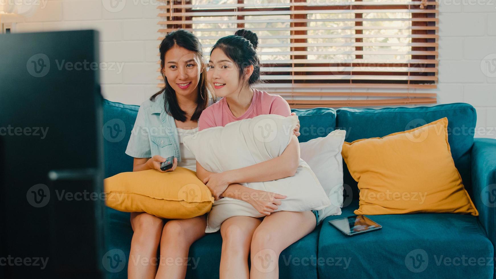 Young Asia Lesbian lgbtq women couple watching TV at home, Asian lover female feeling happy fun laugh looking television series movie together while lying sofa in living room at home concept. photo