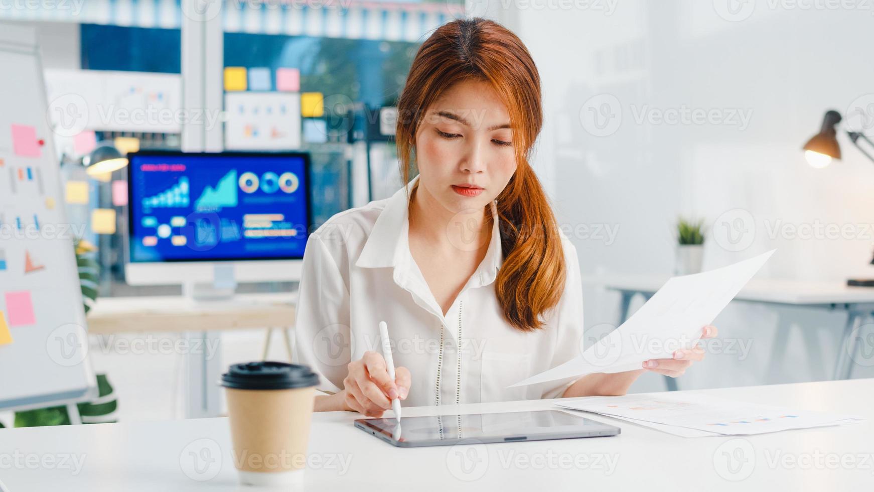 exitosa ejecutiva de asia joven empresaria con ropa informal inteligente dibujando, escribiendo y usando un bolígrafo con una tableta digital pensando en el proceso de trabajo de ideas de búsqueda de inspiración en la oficina doméstica moderna. foto