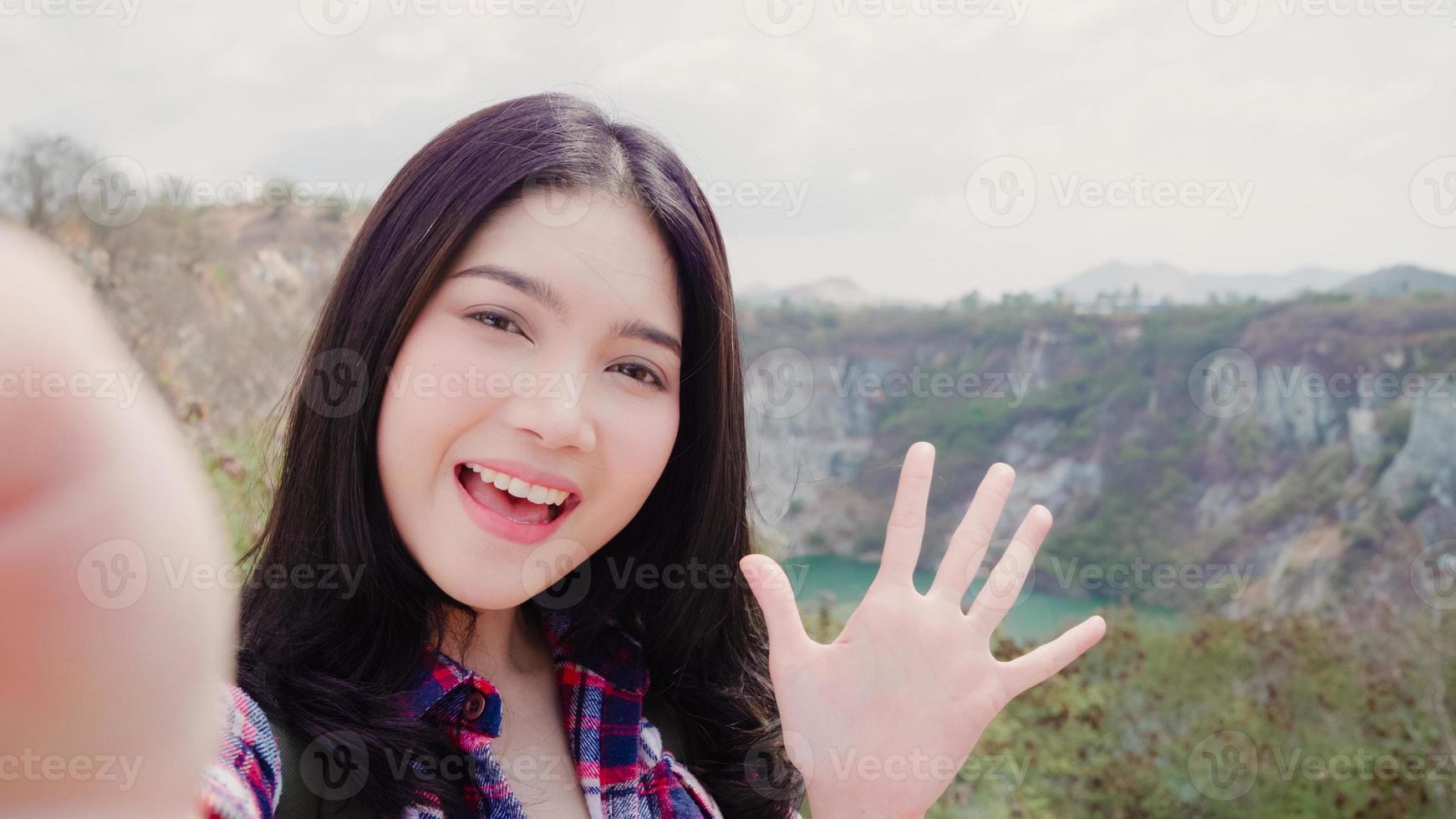 Blogger Asian backpacker woman record vlog video on top of mountain, young female happy using mobile phone make vlog video enjoy holidays on hiking adventure. Lifestyle women travel and relax concept. photo