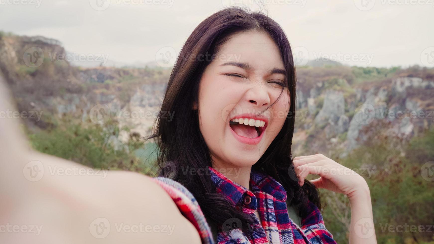 Blogger Asian backpacker woman record vlog video on top of mountain, young female happy using mobile phone make vlog video enjoy holidays on hiking adventure. Lifestyle women travel and relax concept. photo
