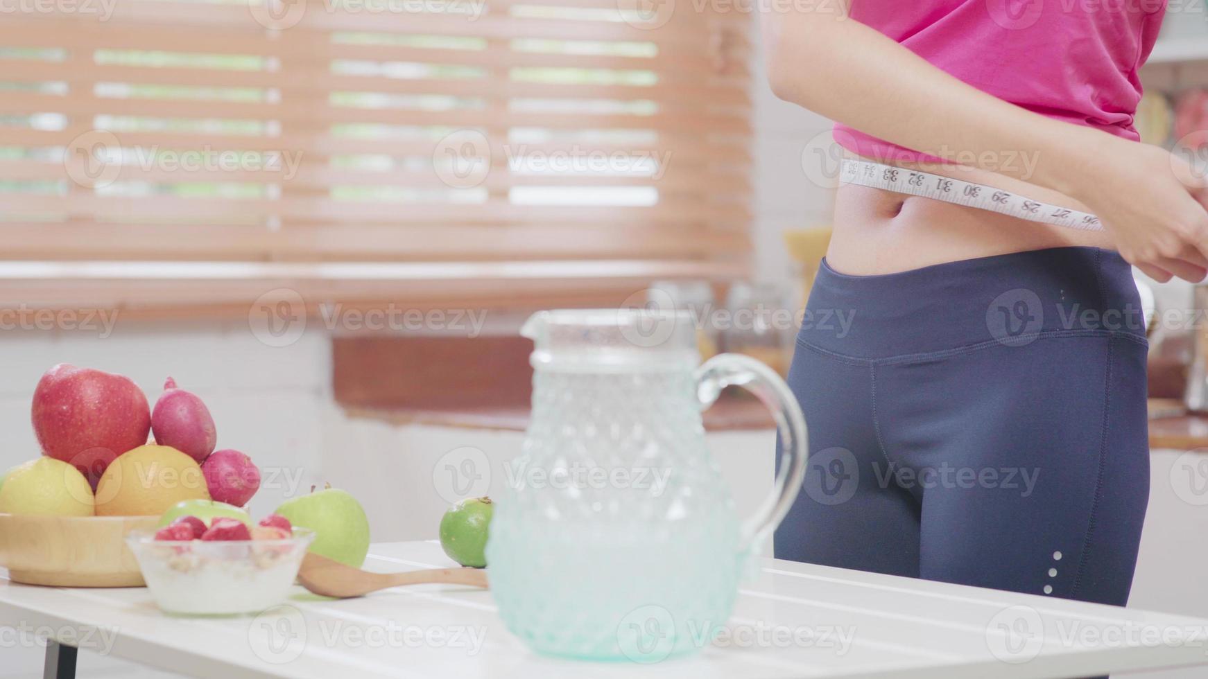 Asian blogger woman make vlog how to diet and lost weight, Young female using camera recording when she drinking water in the kitchen. Lifestyle influencer women healthy concept. photo