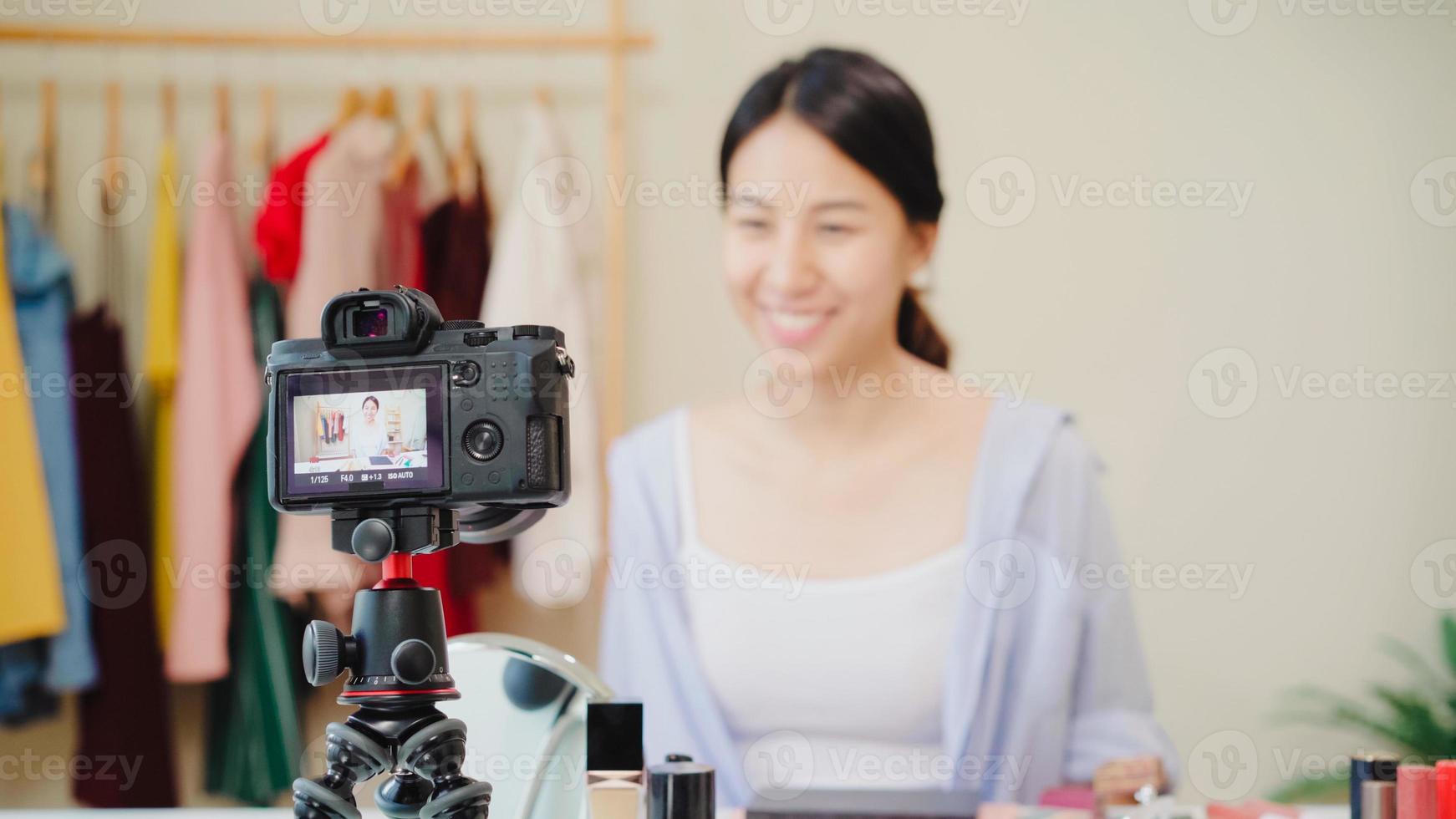 Beauty blogger present beauty cosmetics sitting in front camera for recording video. Beautiful asian woman use cosmetics review make up tutorial broadcast live video to social network by internet. photo