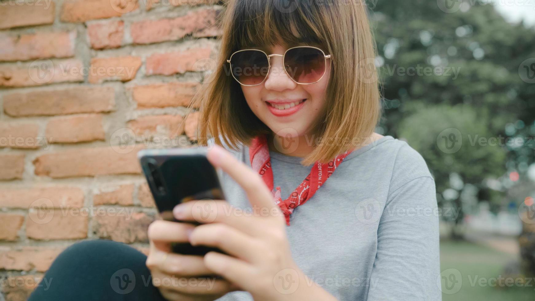 mujer asiática viajera que usa un teléfono inteligente revisando las redes sociales mientras se relaja después de pasar un viaje de vacaciones en ayutthaya, tailandia, la mujer disfruta de su viaje en un hito increíble en la ciudad tradicional. foto