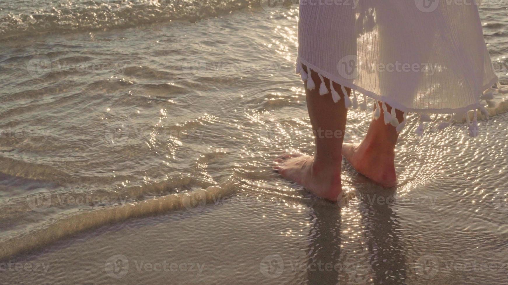 Young Asian woman walking on beach. Beautiful female happy relax walking on beach near sea when sunset in evening. Lifestyle women travel on beach concept. photo