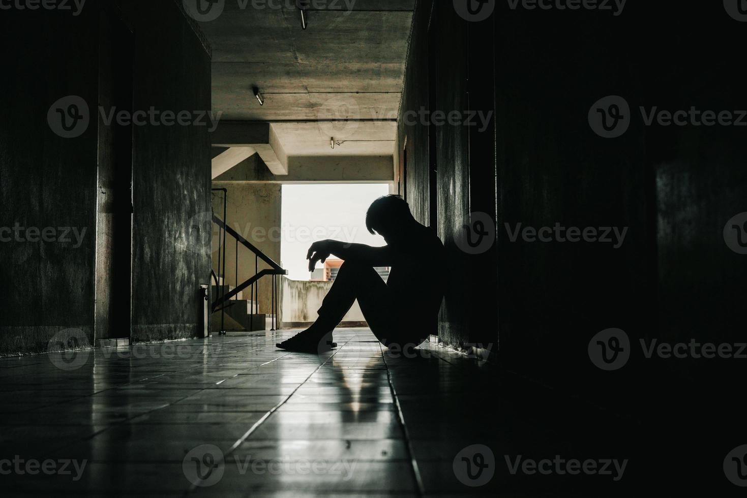 dramática, silueta de un hombre triste y deprimido sentado con la cabeza en las manos en el suelo. hombre triste, llanto, drama, concepto solitario e infeliz. foto