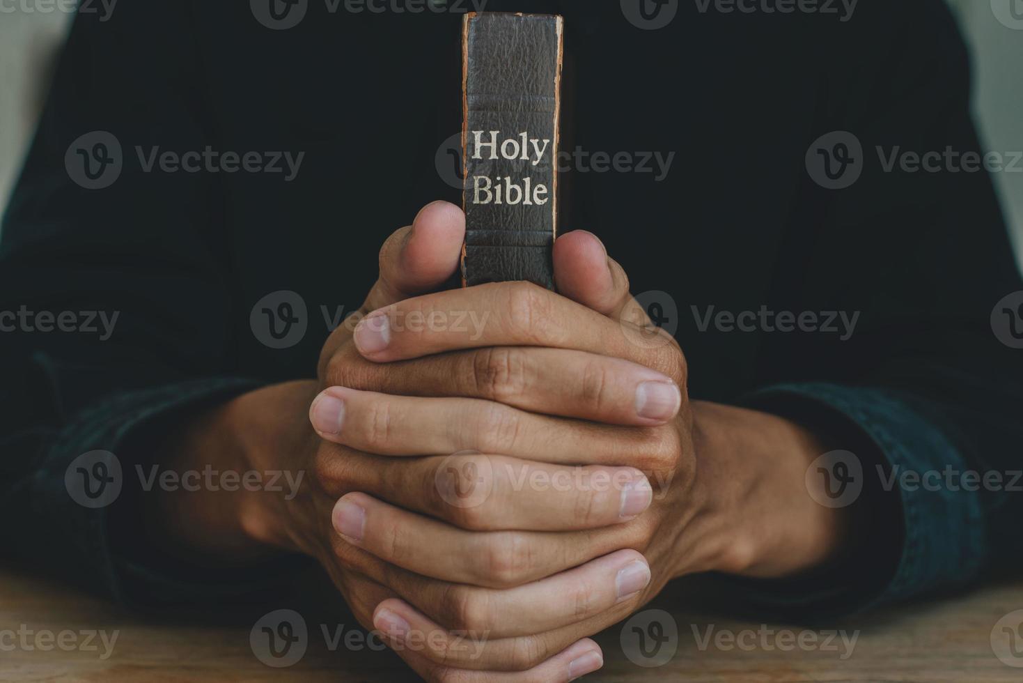 Hands of a man praying over a Bible represents faith and spirituality in everyday life. close up. photo