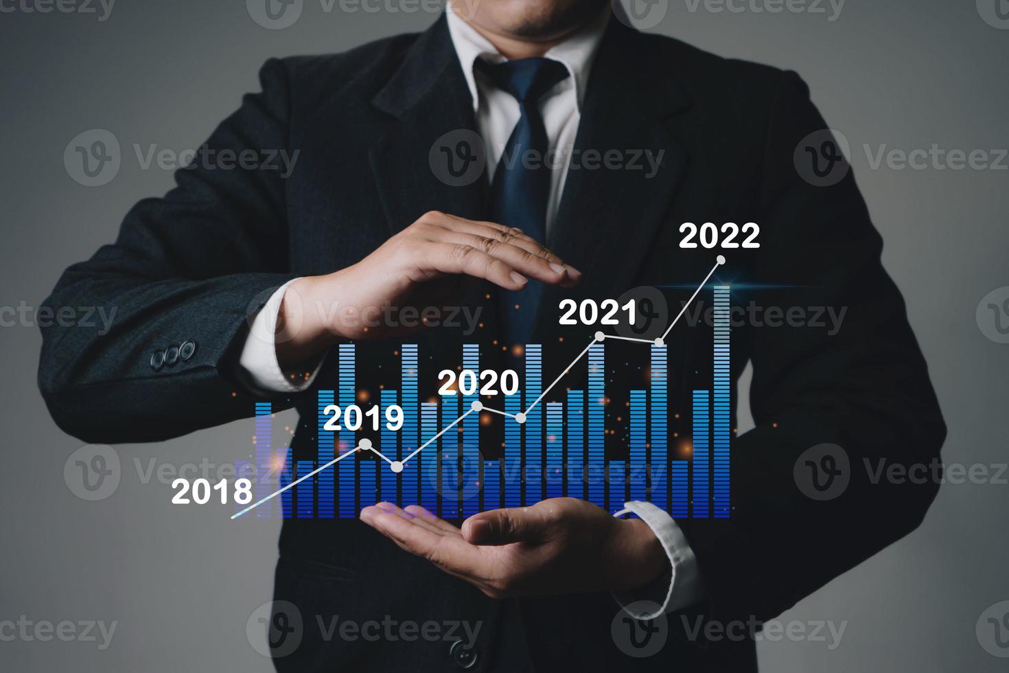 Close up of businessman hand holding trend chart growing up from 2021 to 2022 on grey background, Business investment growth up concept. photo