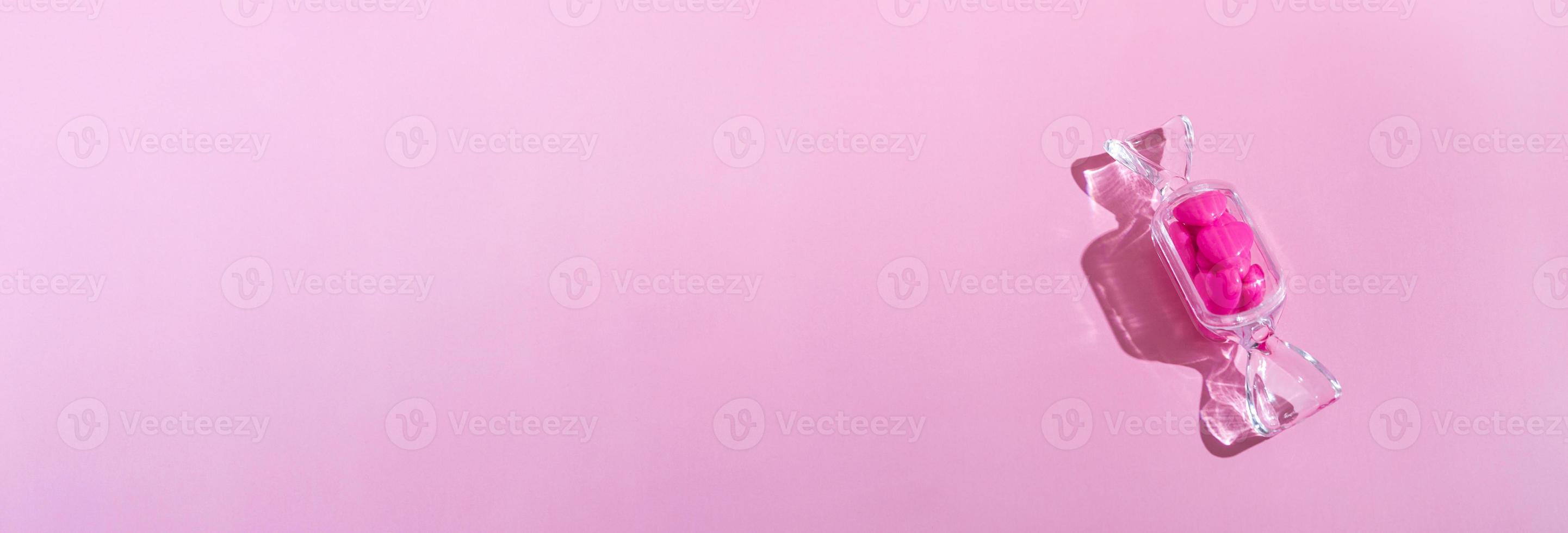 Transparent candy shaped box with sweet heart lollipops with hard shadow on pink background copy space. The concept of Valentines day, mothers day. photo