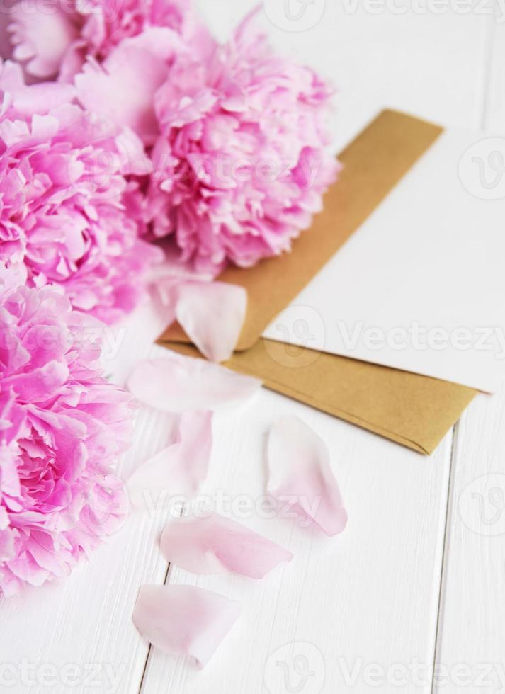 invitation card, craft envelope and pink peony flowers photo