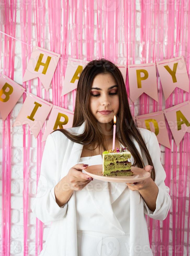 hermosa mujer emocionada celebrando un cumpleaños sosteniendo un pastel pidiendo un deseo foto