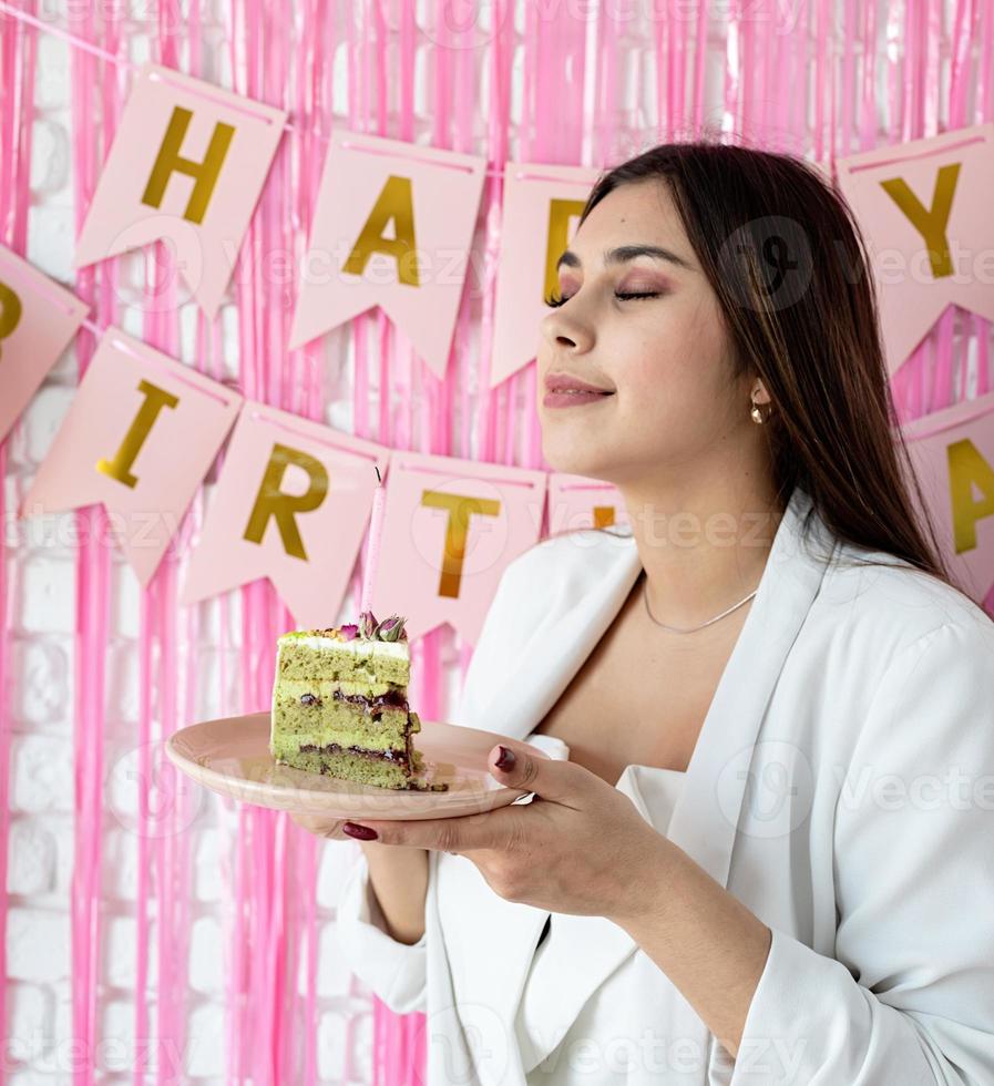 Beautiful excited woman celebrating birthday holding cake making wish photo