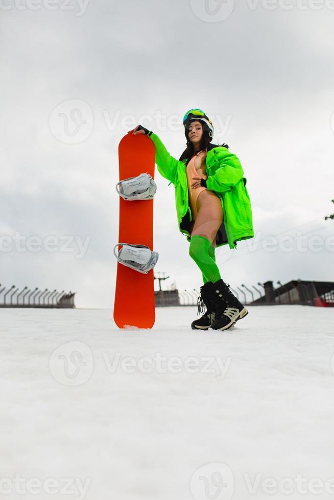 Young beautiful woman posing with a snowboard on a ski slope photo