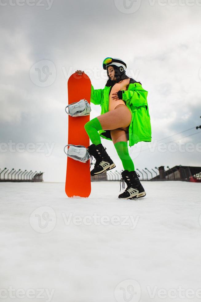 Young beautiful woman posing with a snowboard on a ski slope photo